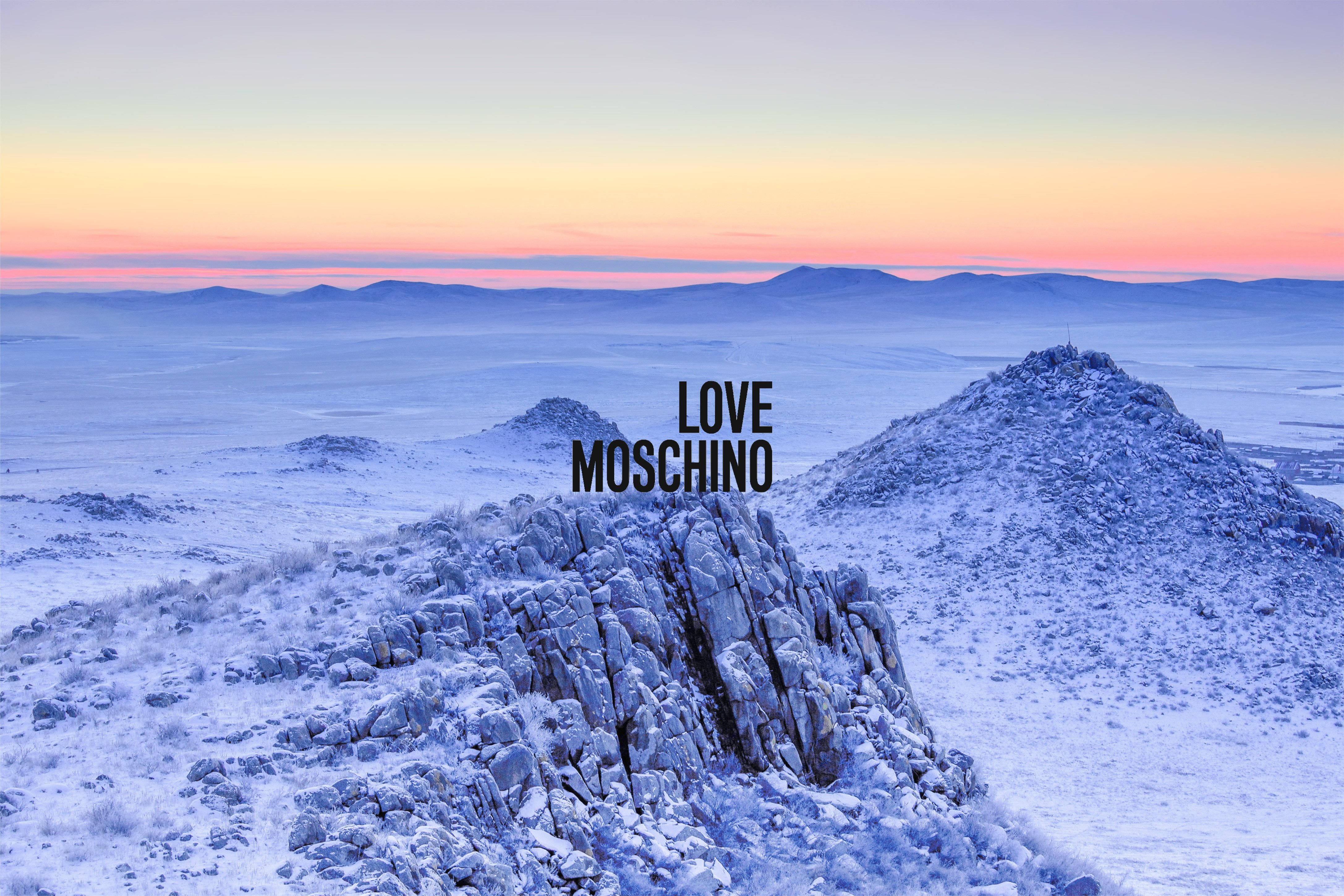 moschino 桌布 壁紙 — 白雪覆蓋崎嶇的岩石和遠山，在柔和的粉紅色和橙色日出天空下。
