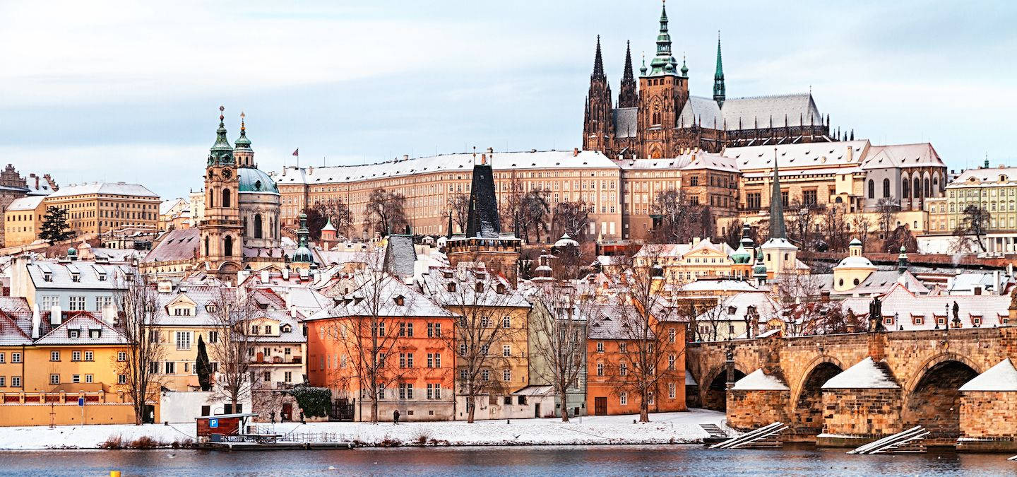 Europe 桌布 壁紙 — 白雪覆蓋布拉格的歷史屋頂和查理大橋，在蒼白的冬日天空下。