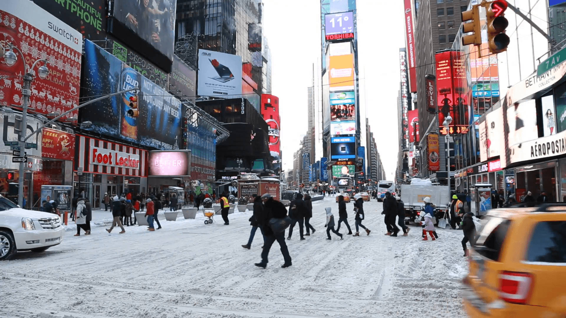 USA 桌布 壁紙 — 白雪覆蓋時代廣場，行人穿梭於繁華的街道，兩旁是高聳的數位廣告看板和黃色計程車。