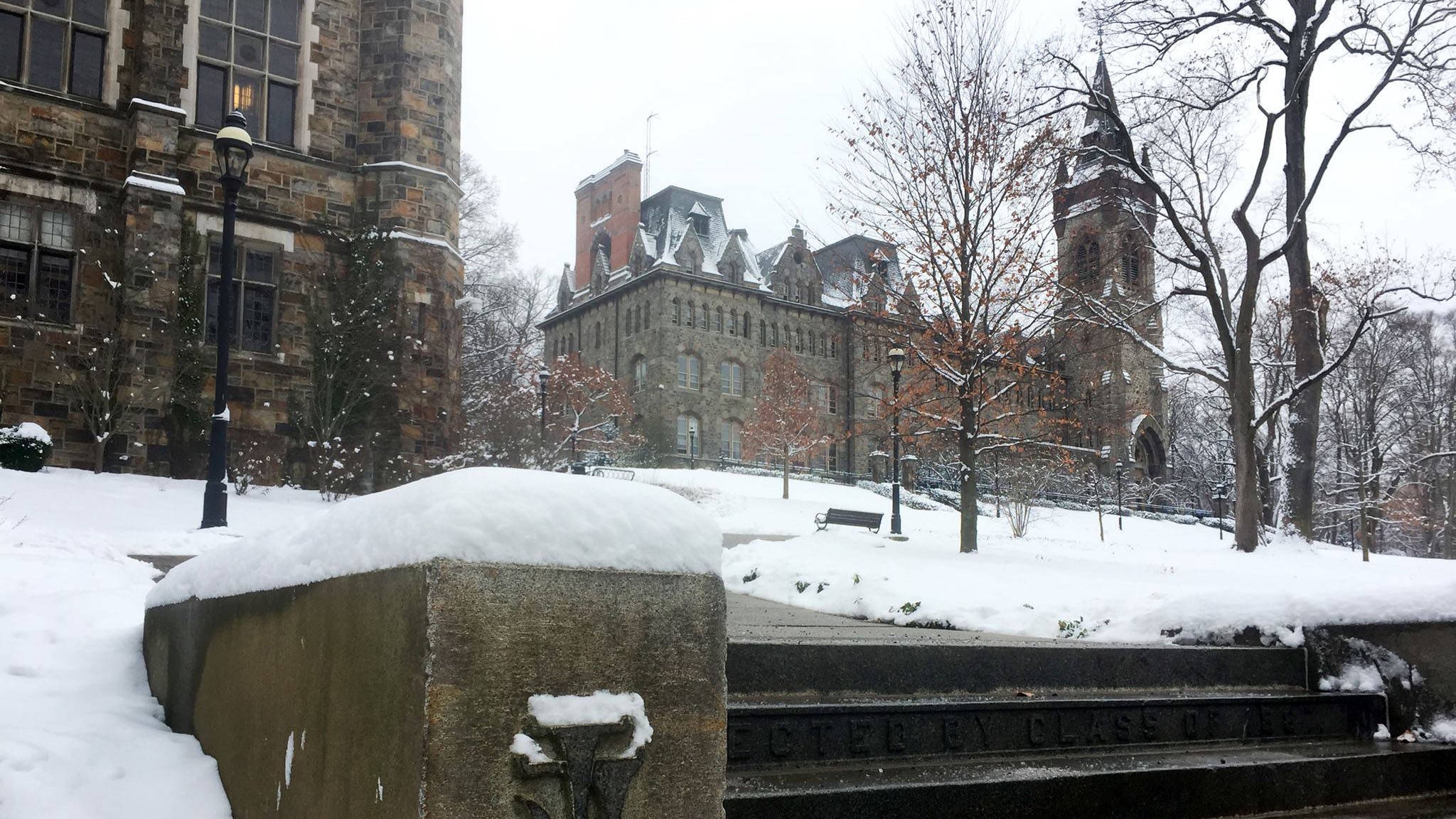 冬天 桌布 壁紙 — 白雪覆蓋歷史悠久的石建築和光禿禿的樹木，在陰天下的寧靜校園庭院。