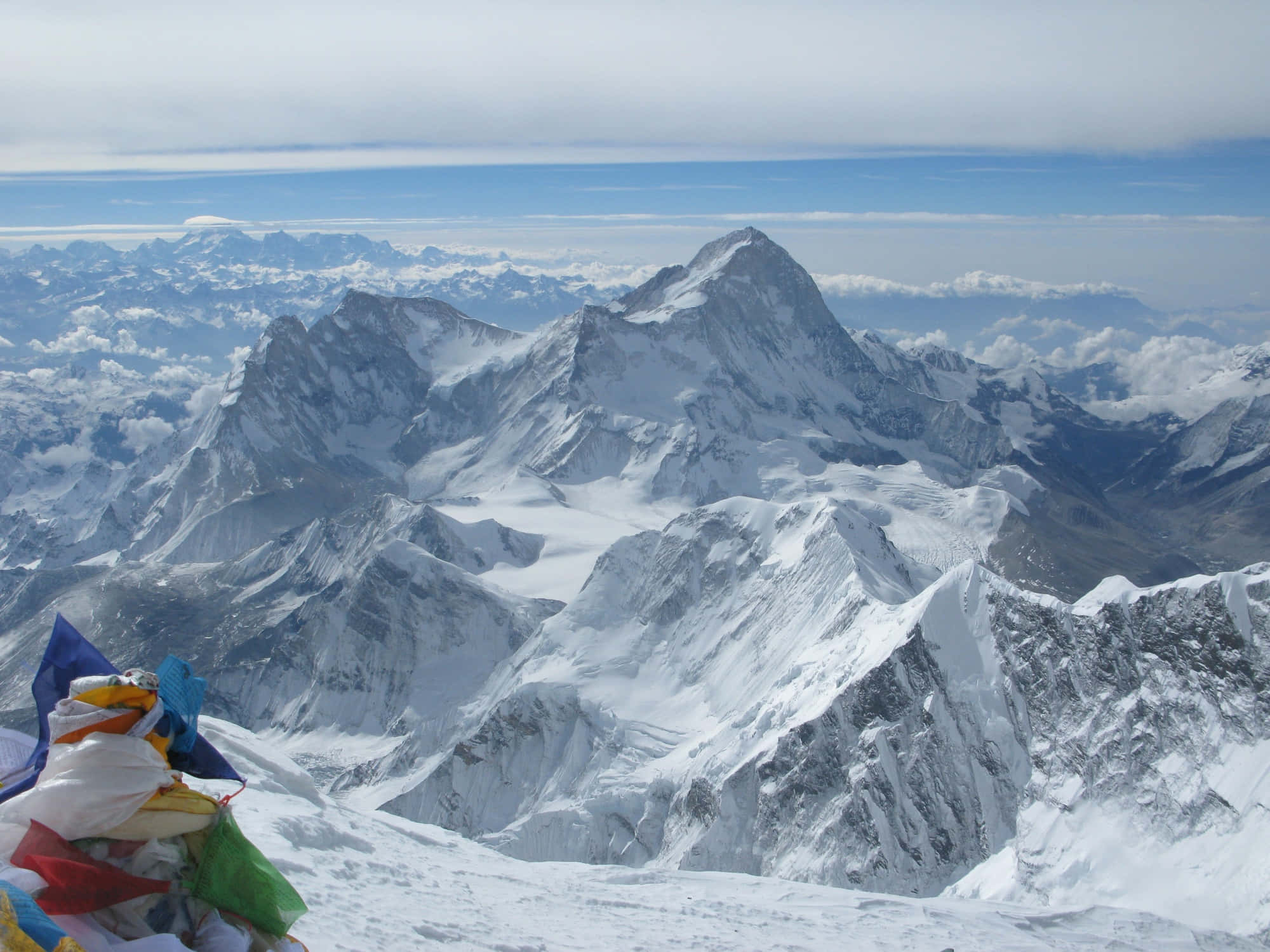 Mount Everest 桌布 壁紙 — 白雪覆蓋的喜馬拉雅山峰穿破雲層，前景有經幡飄揚。
