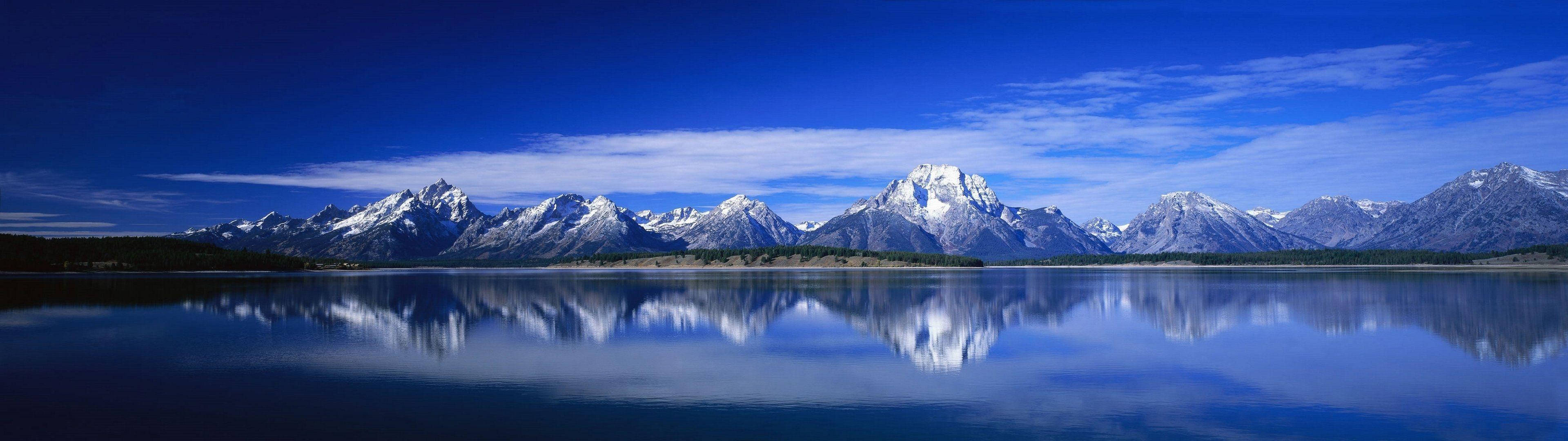 Lake 桌布 壁紙 — 白雪覆蓋的大提頓峰在深藍色天空和縷縷白雲下，完美倒映在玻璃般清澈的高山湖泊中。