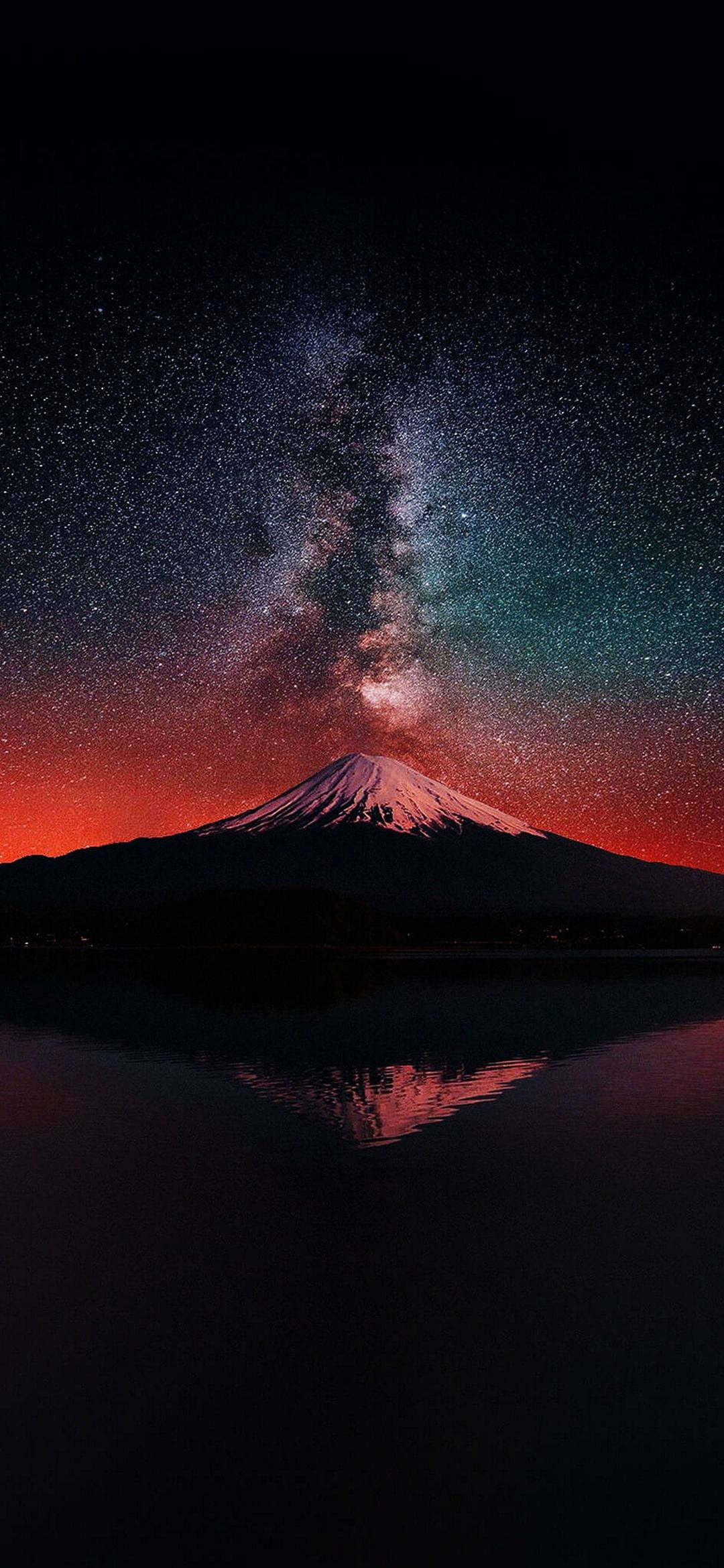 AMOLED 桌布 壁紙 — 白雪覆蓋的富士山在充滿活力的星空下形成剪影，銀河拱橋般橫跨天際，倒映在下方平靜的水面上。