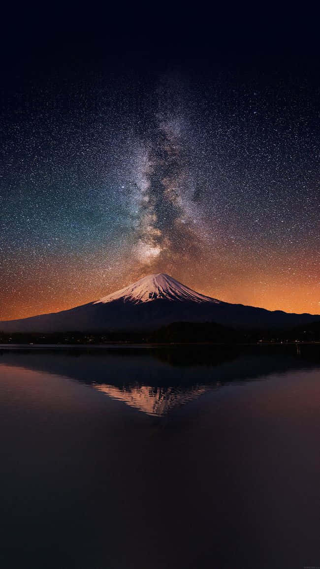 桌布 壁紙 — 白雪覆蓋的富士山在平靜的水面上完美倒映，上方是璀璨星空，銀河拱橋般橫跨天際。