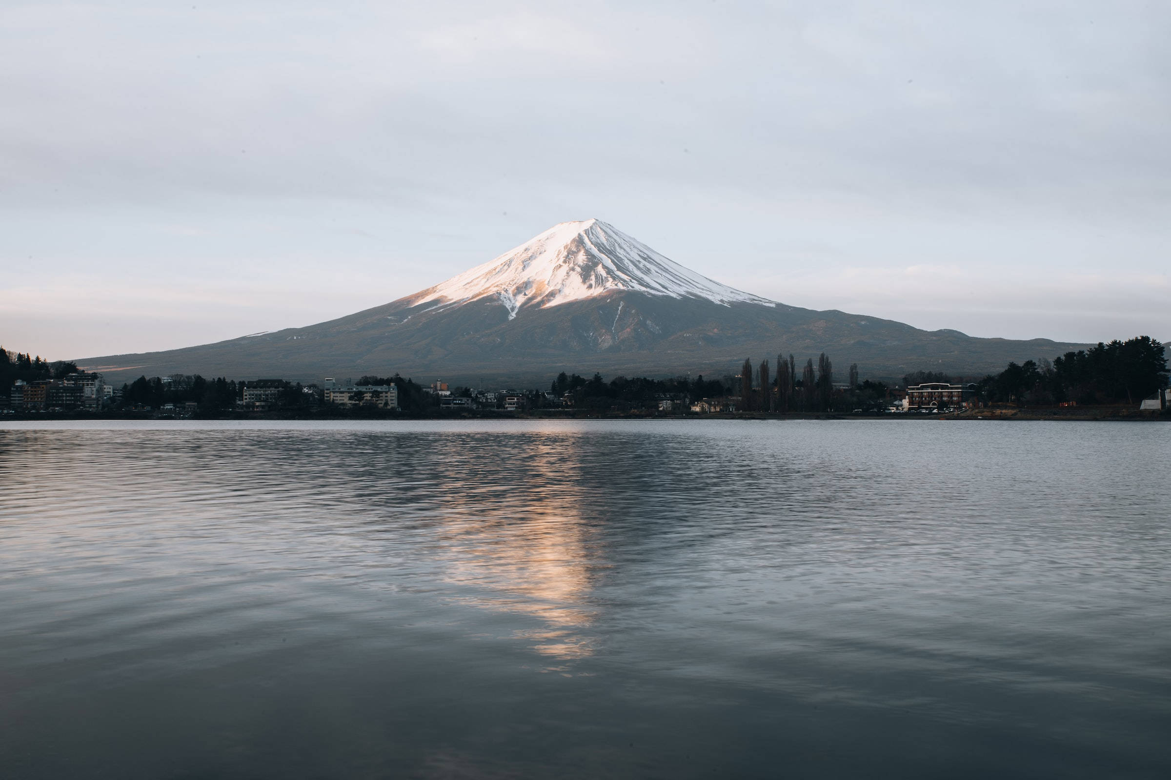 富士山 桌布 壁紙 — 白雪覆蓋的富士山在平靜的水面上寧靜地倒映，上方是柔和的黎明天空。