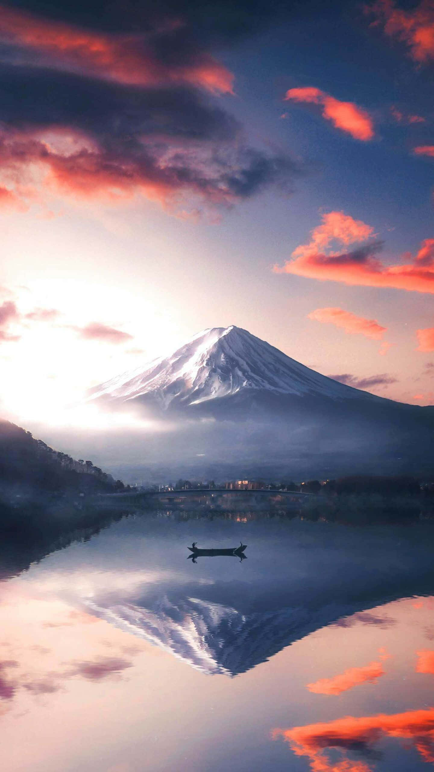自然 桌布 壁紙 — 白雪覆蓋的富士山在平靜的湖面上完美倒映，一艘孤獨的小船在燃燒般夕陽雲彩繪成的天空下滑行。