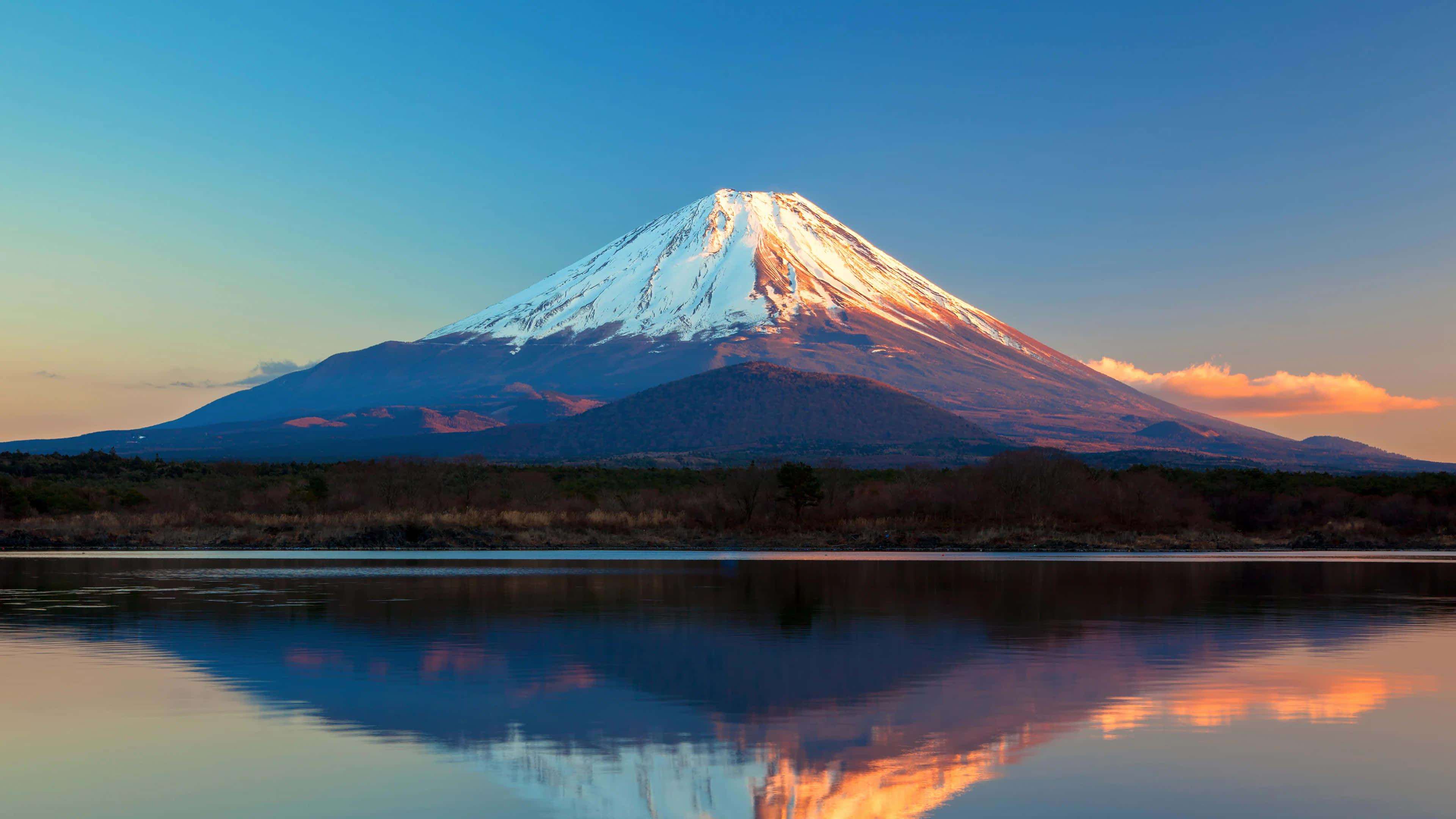 Mt Fuji 桌布 壁紙 — 白雪覆蓋的富士山在日落時分完美倒映在平靜的水面上，上方有溫暖的橙色雲彩。