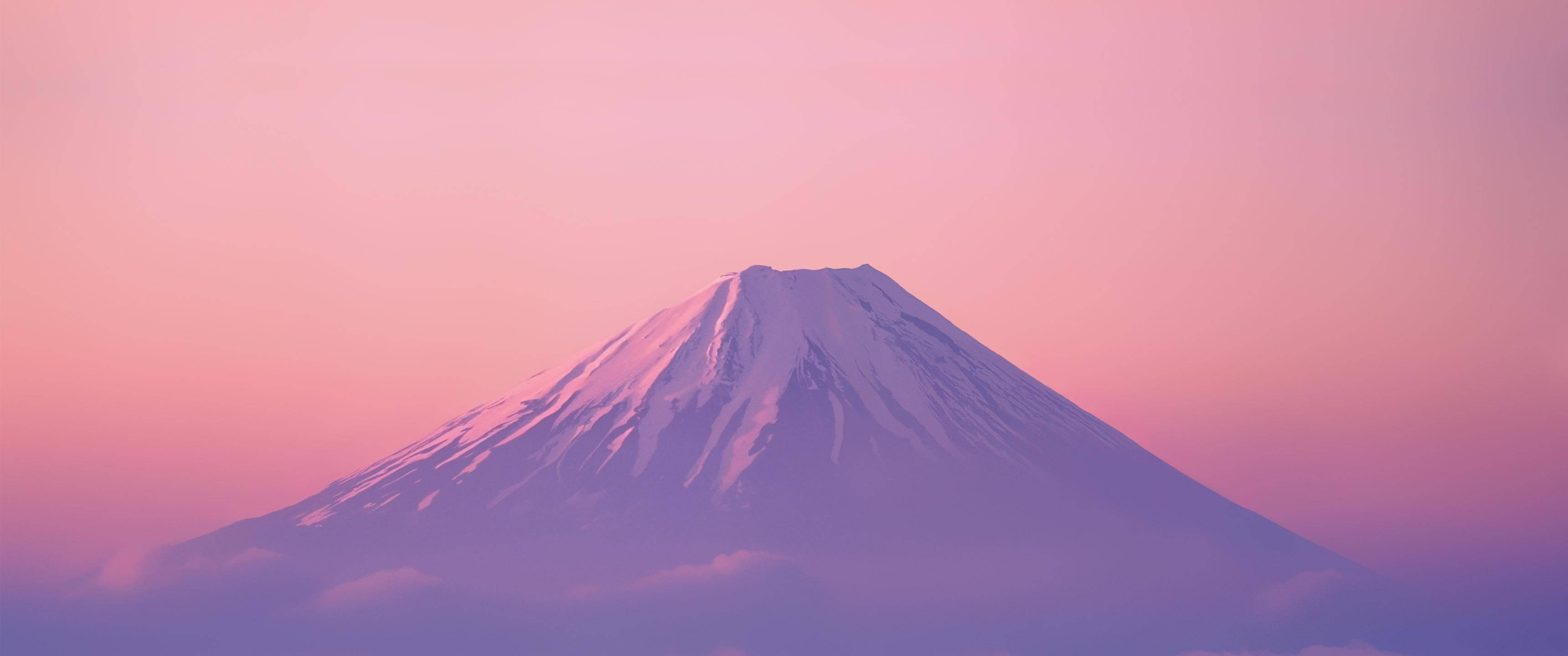 山景 桌布 壁紙 — 白雪覆蓋的富士山在柔和的粉紅色和紫色暮色天空下，穿過薄霧雄偉地聳立。