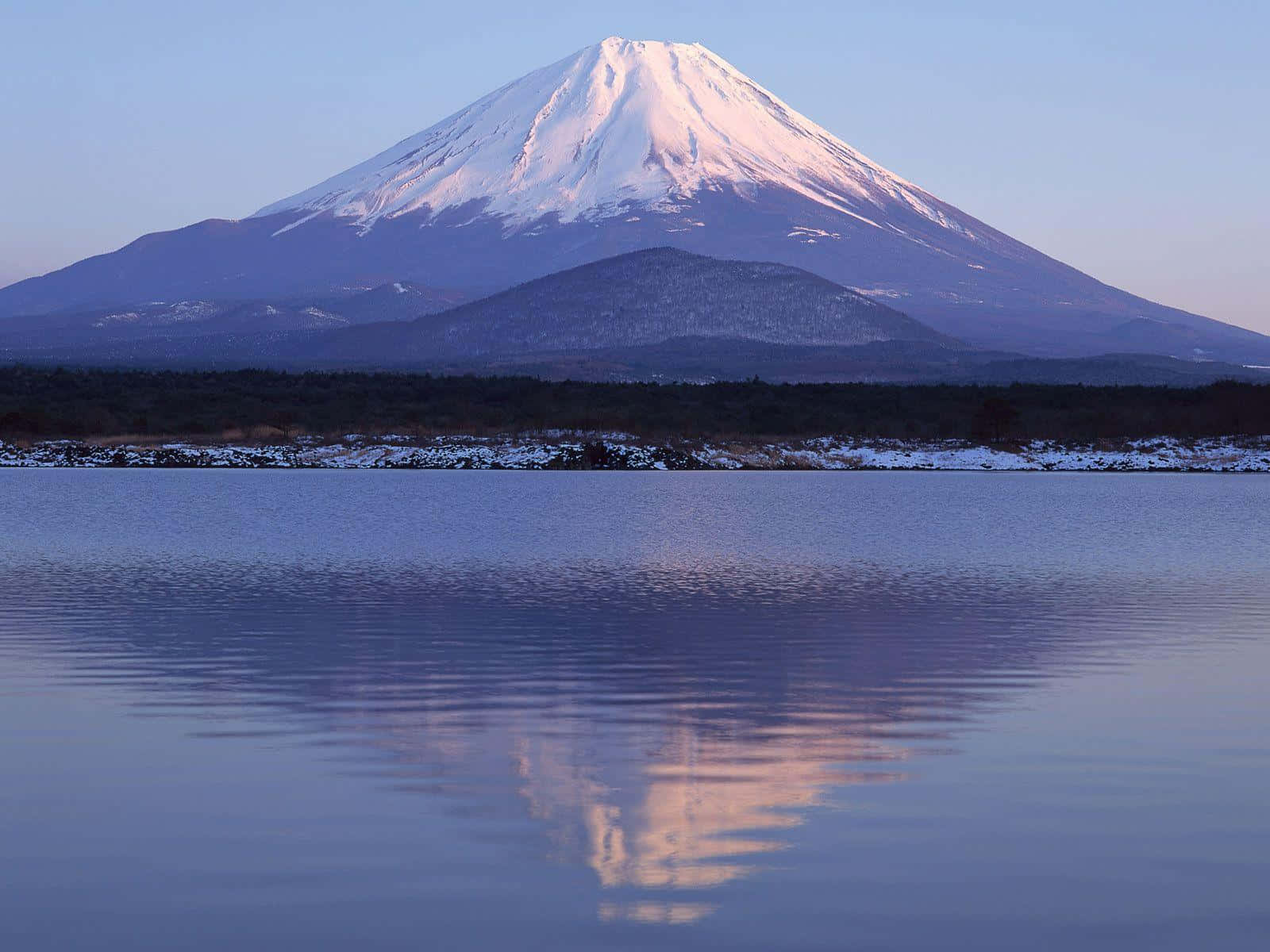 Mt Fuji 桌布 壁紙 — 白雪覆蓋的富士山在黎明時分平靜地倒映在寧靜的湖面上，帶有柔和的紫色和藍色色調。