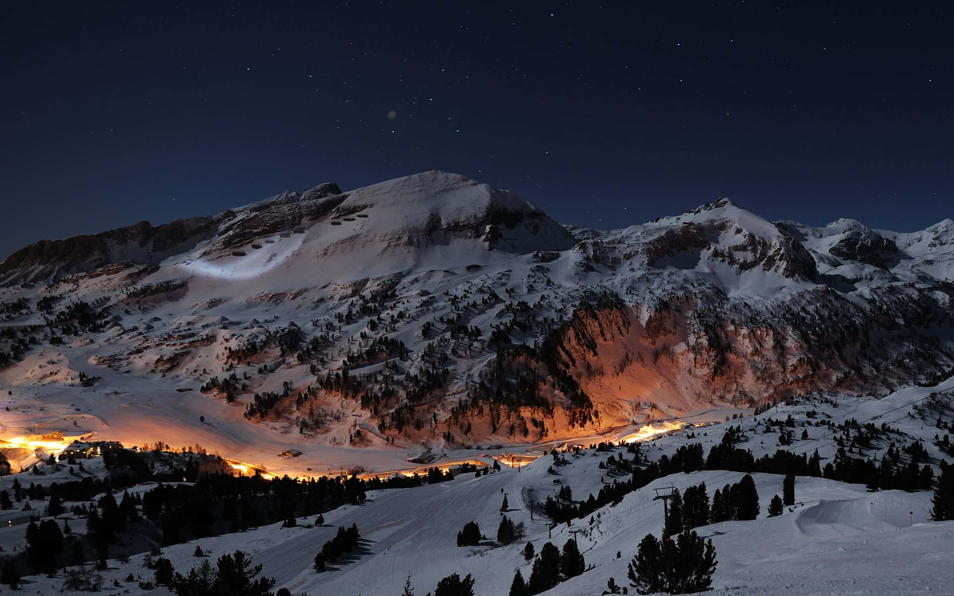 Best Winter 桌布 壁紙 — 白雪覆蓋的山峰，在繁星點點的夜空下，山谷中閃爍著溫暖的燈光。