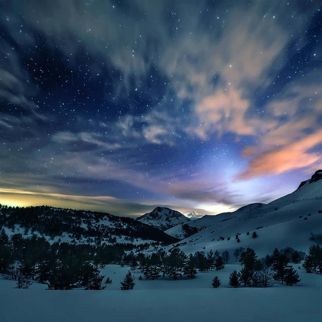 Mountain Scenery 桌布 壁紙 — 白雪覆蓋的山峰，在繁星點點的夜空下，地平線上有柔和的粉紅色和藍色雲彩發光。