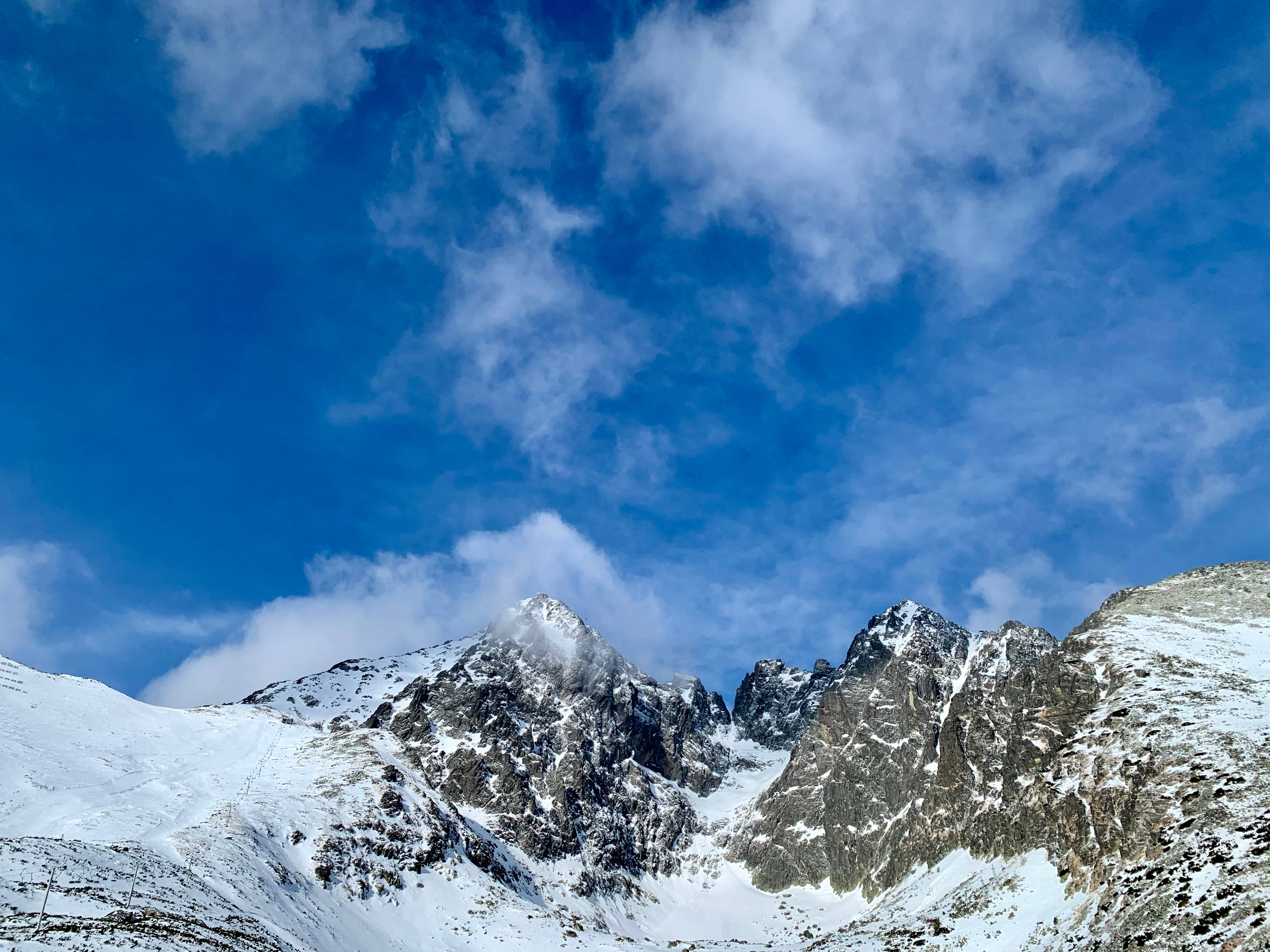 Slovakia 桌布 壁紙 — 白雪覆蓋的山峰刺穿了一片充滿活力的藍天，天空中有縷縷白雲。
