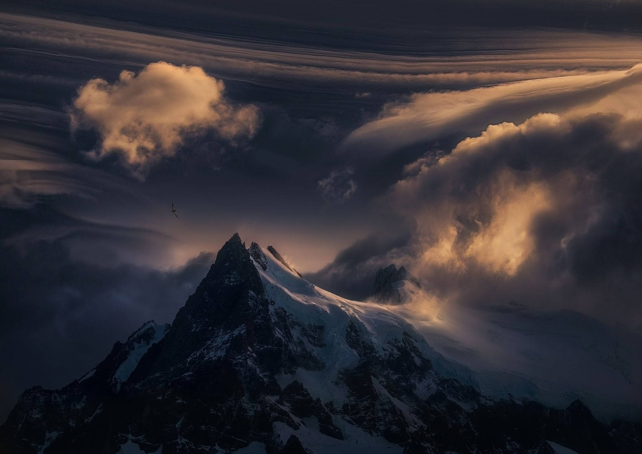 Patagonia 桌布 壁紙 — 白雪覆蓋的山峰刺穿沐浴在金色日落光芒中的戲劇性雲層。
