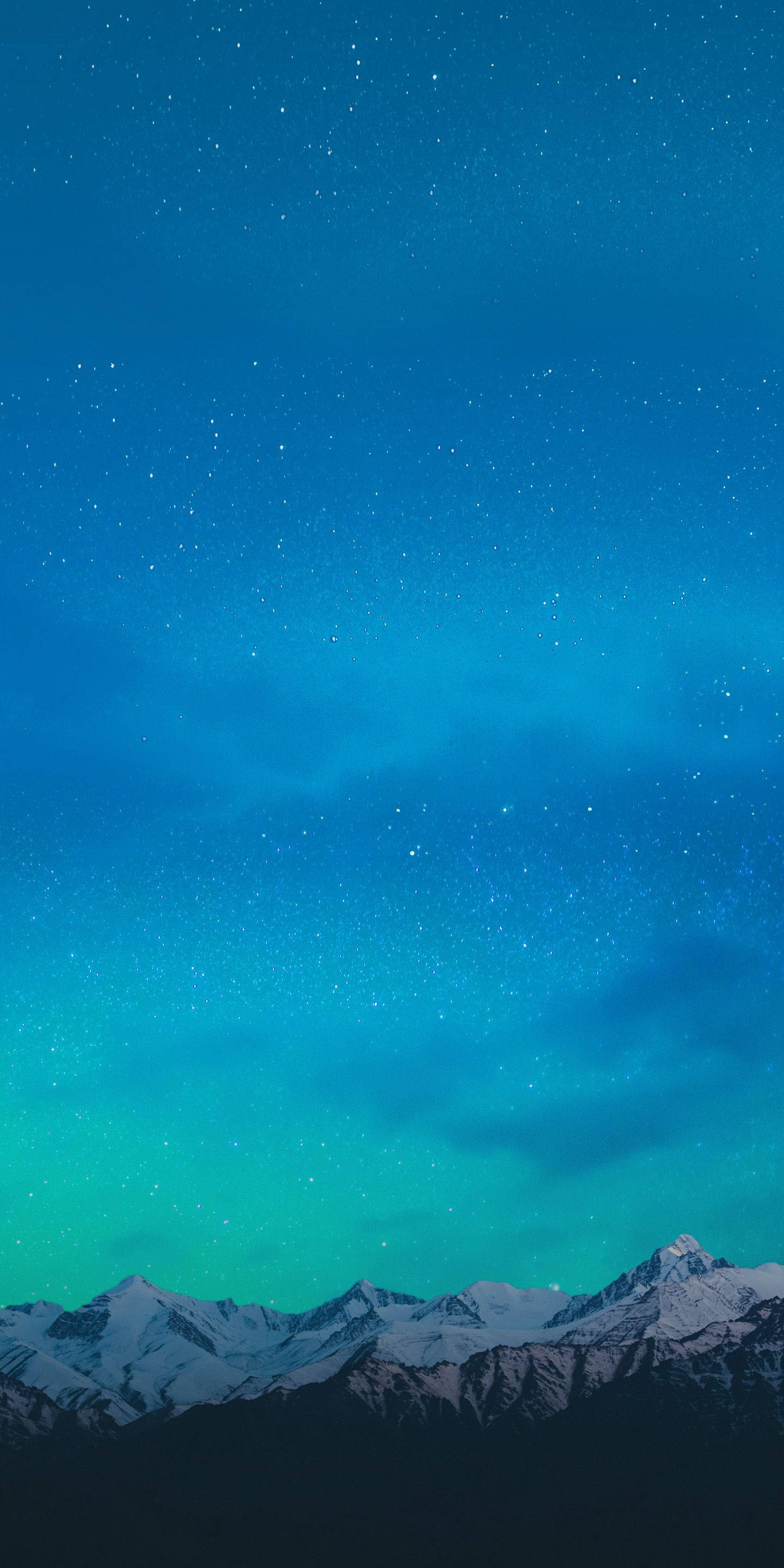 Best Smartphone 桌布 壁紙 — 白雪覆蓋的山峰在充滿活力的星空下升起，閃爍著藍綠色和深藍色的極光。