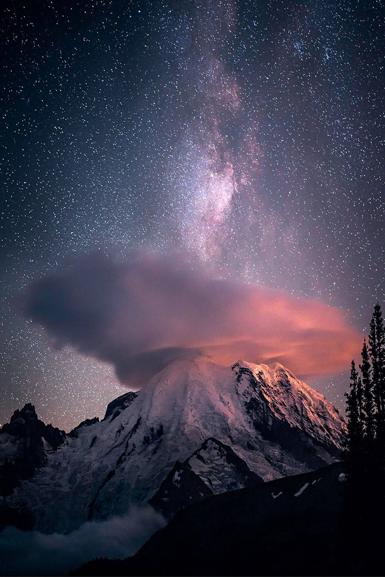 iPhone 桌布 壁紙 — 白雪覆蓋的山峰在充滿活力的星空下升起，銀河穿過粉紅色的雲層閃耀。