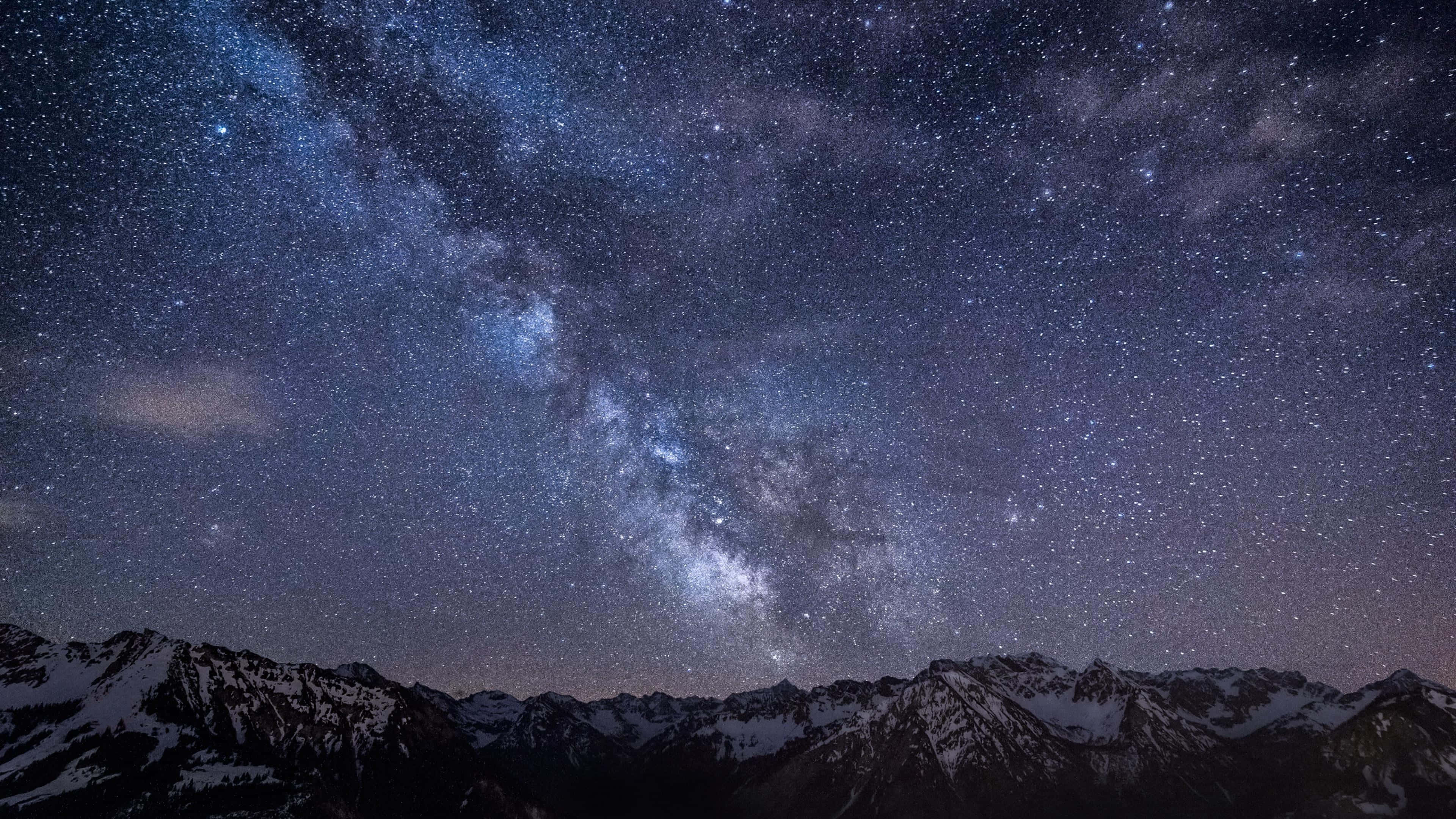 Star Sky 桌布 壁紙 — 白雪覆蓋的山峰在壯麗的星空下聳立，銀河明亮地閃耀。
