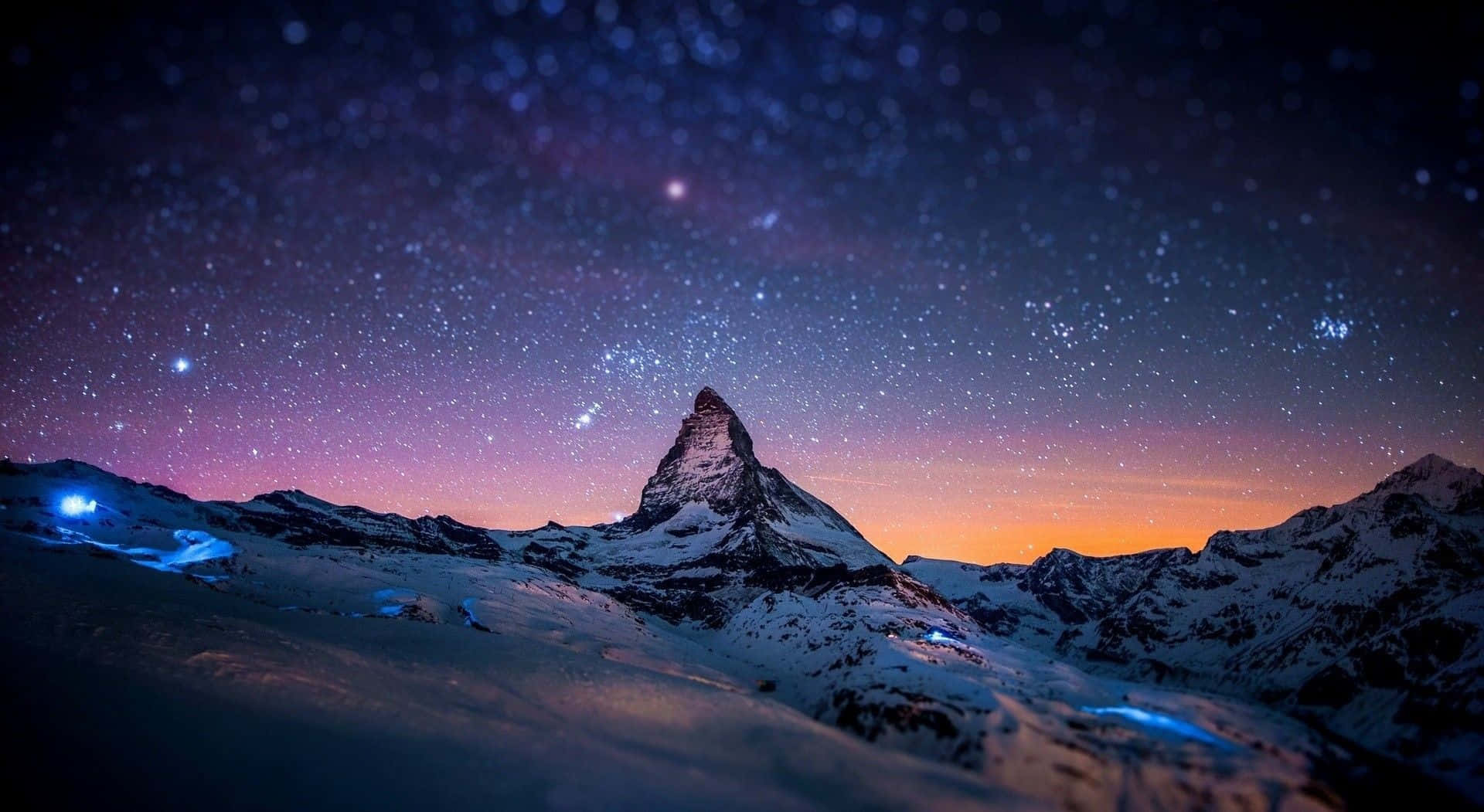Chilly Night 桌布 壁紙 — 白雪覆蓋的山峰在帶有紫色和橙色色調的星空暮色天空下聳立。