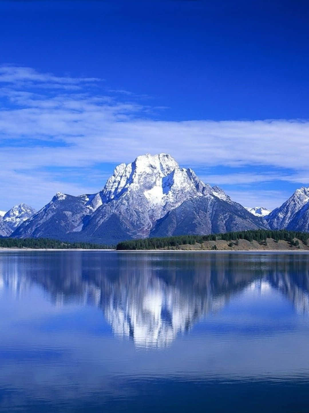 Lake 桌布 壁紙 — 白雪覆蓋的山峰在平靜的湖泊後方巍峨聳立，清澈的藍天下，湖面倒映著它們的影子。