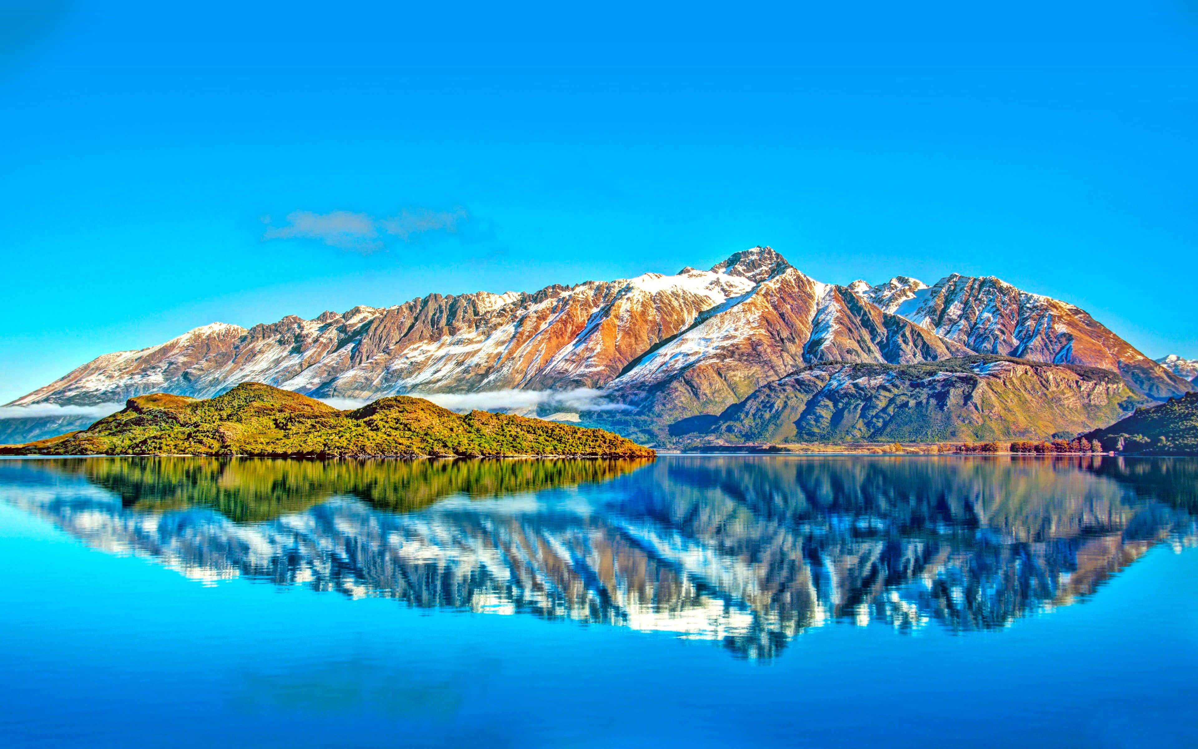風景動畫 桌布 壁紙 — 白雪覆蓋的山峰在平靜的湖泊後方雄偉地升起，湖面映照著它們的山巔，背景是清澈的藍天。