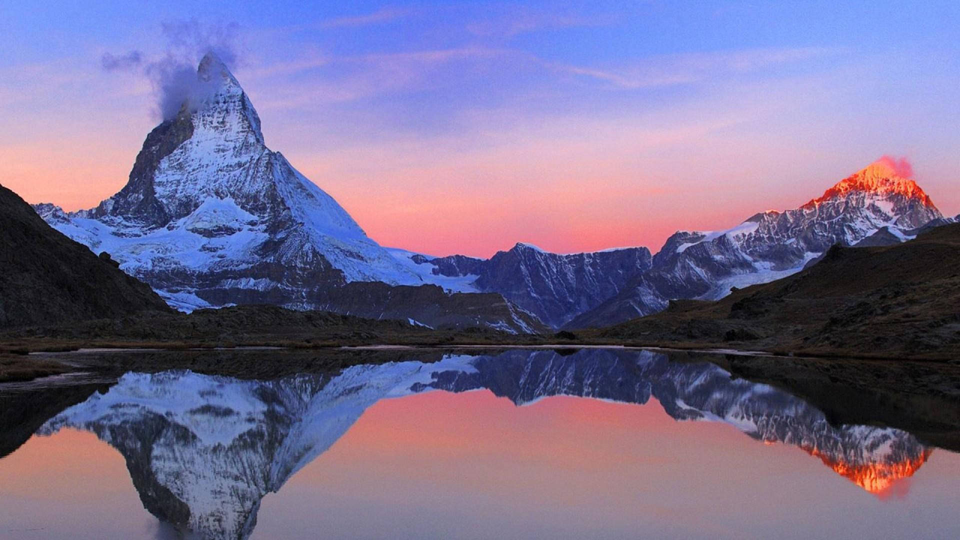 藝術 桌布 壁紙 — 白雪覆蓋的山峰在日落時分完美倒映在平靜的高山湖泊中，天空呈現粉紅和藍色。