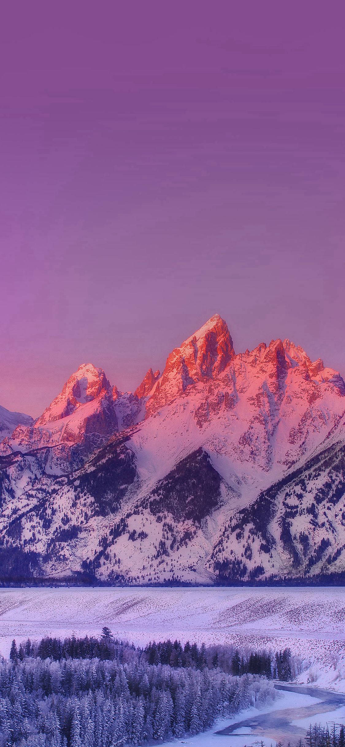 美學 iPhone 壁紙 桌布 壁紙 — 白雪覆蓋的山峰在暮色中於冰凍的湖泊和雪林之上閃耀著粉紅色和紫色。