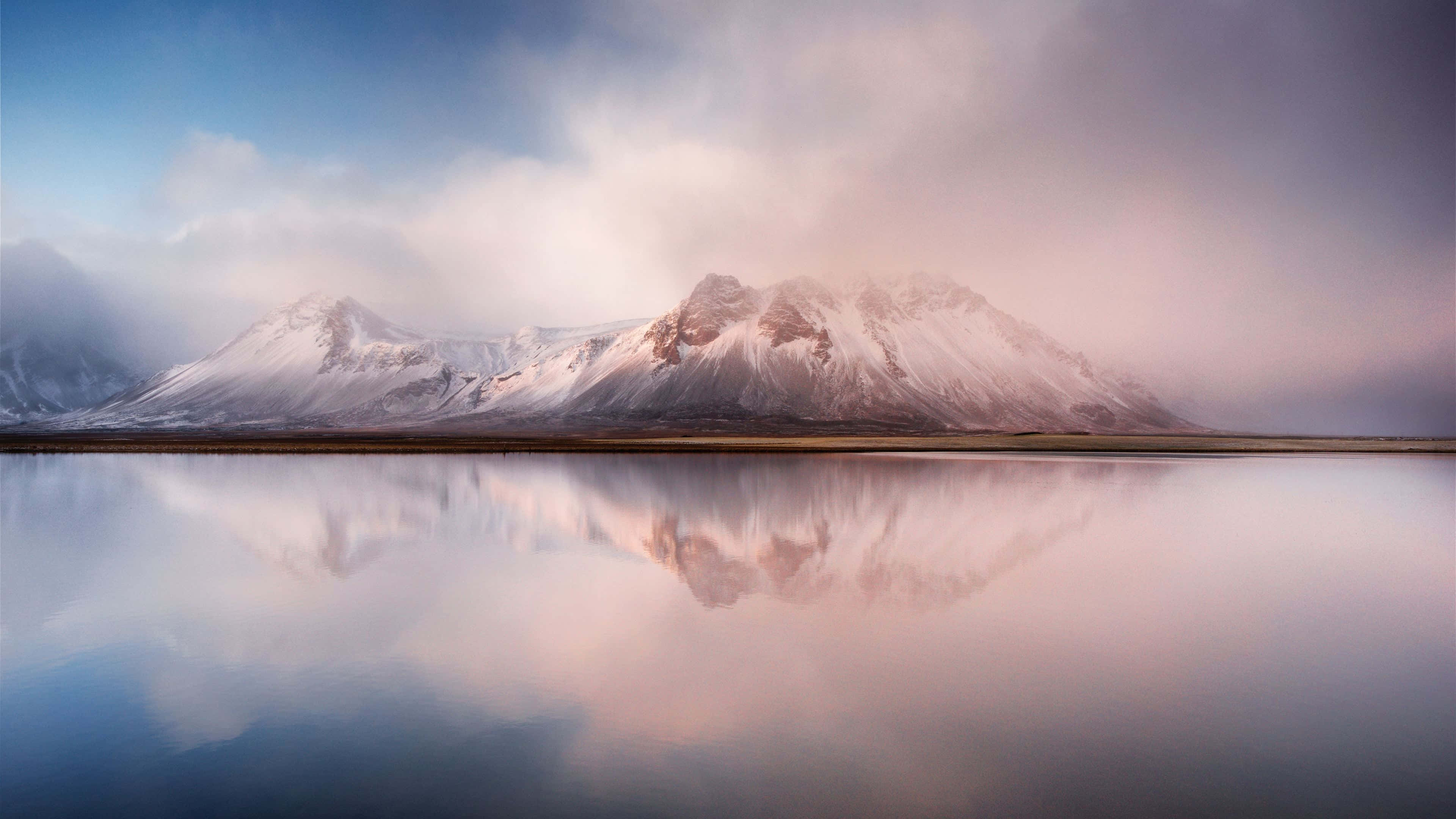 Nature Scenes 桌布 壁紙 — 白雪覆蓋的山峰在柔和粉紅與藍色的黎明天空下，完美倒映在玻璃般的湖面上。
