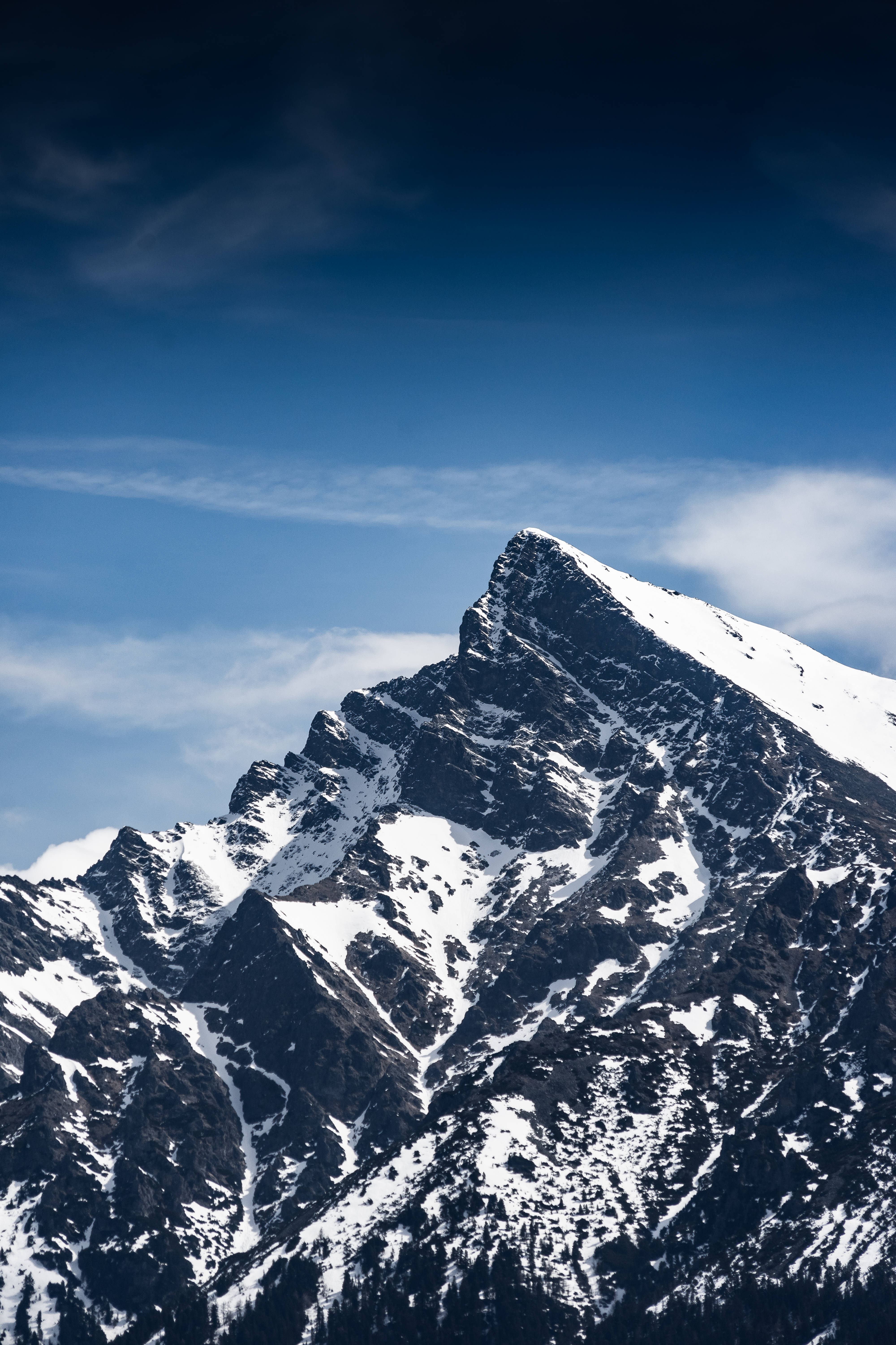 HD Mountain 桌布 壁紙 — 白雪覆蓋的山峰在深藍色的天空和縷縷薄雲中巍然聳立。