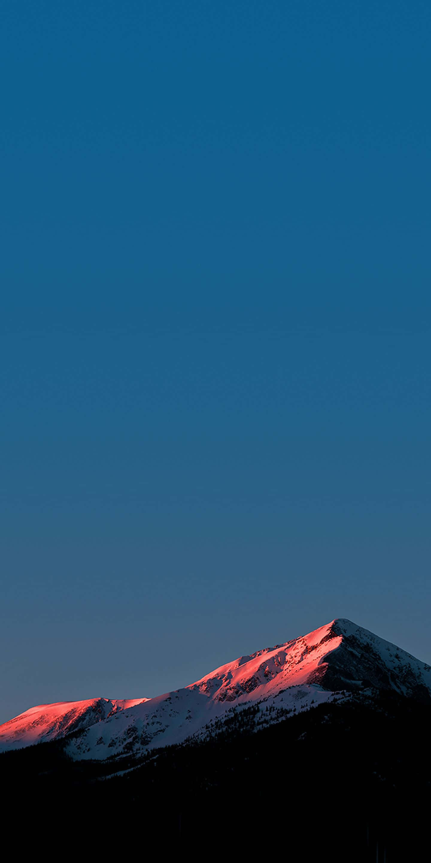 4K Super Amoled Phone 桌布 壁紙 — 白雪覆蓋的山峰在深藍色的暮色天空中散發出溫暖的粉紅色光芒。
