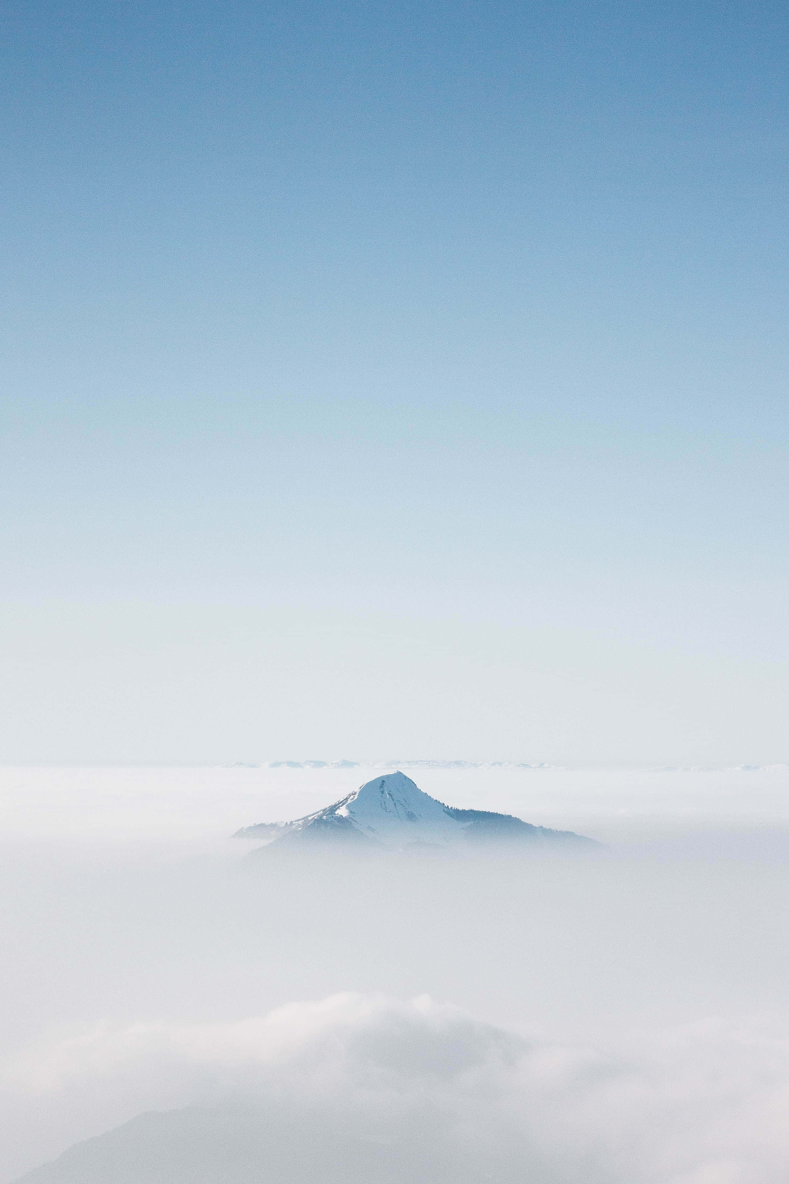 山景 桌布 壁紙 — 白雪覆蓋的山峰在清澈的藍天下，寧靜地聳立在雲海之上。