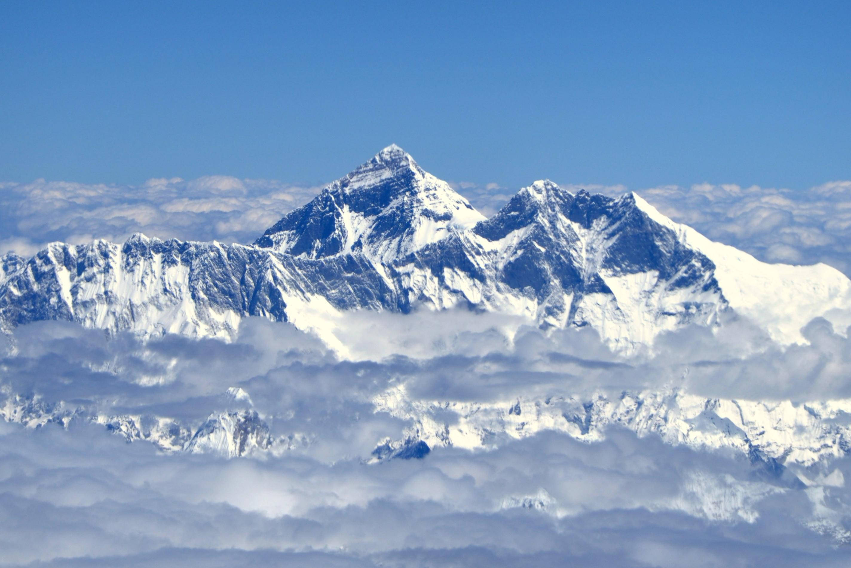 山景 桌布 壁紙 — 白雪覆蓋的山峰在清澈的藍天下穿過雲海。