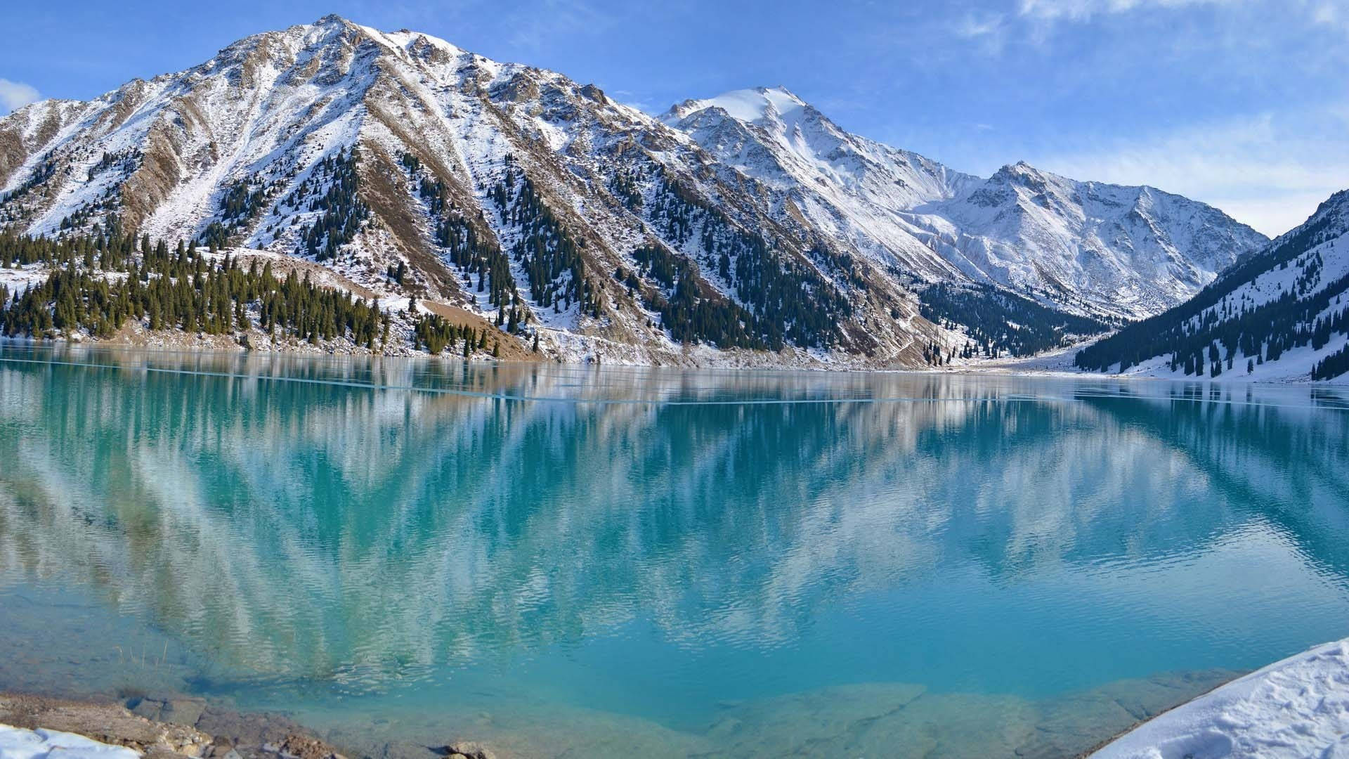 Lake 桌布 壁紙 — 白雪覆蓋的山峰在清澈碧藍的湖水中完美倒映，天空湛藍無雲。