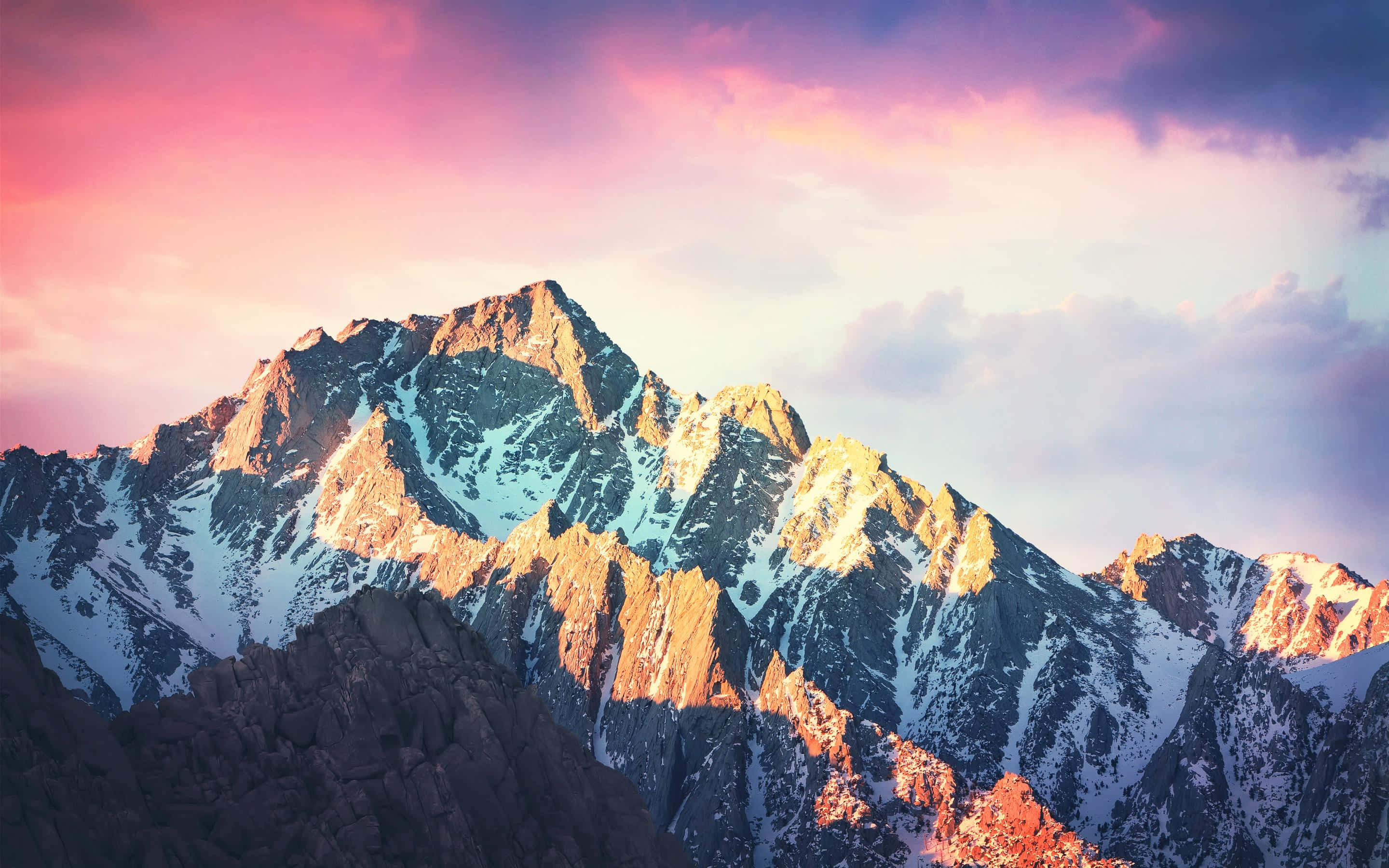 macOS 桌布 壁紙 — 白雪覆蓋的山峰在溫暖的日落光芒中閃耀，映襯著充滿活力的粉紅色和紫色天空。