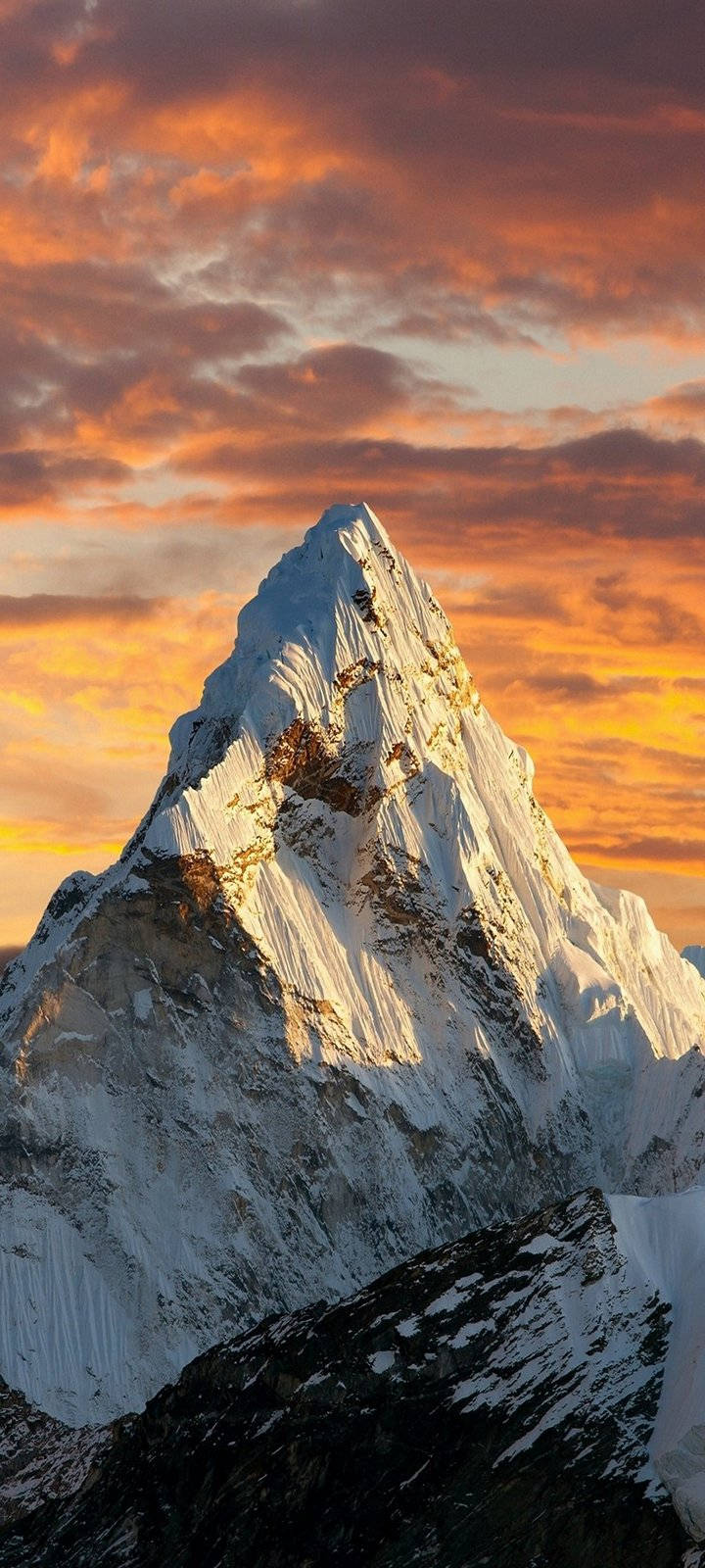 山景 桌布 壁紙 — 白雪覆蓋的山峰在火紅橙色和粉紅色的日落天空下閃耀，伴隨著戲劇性的雲層。