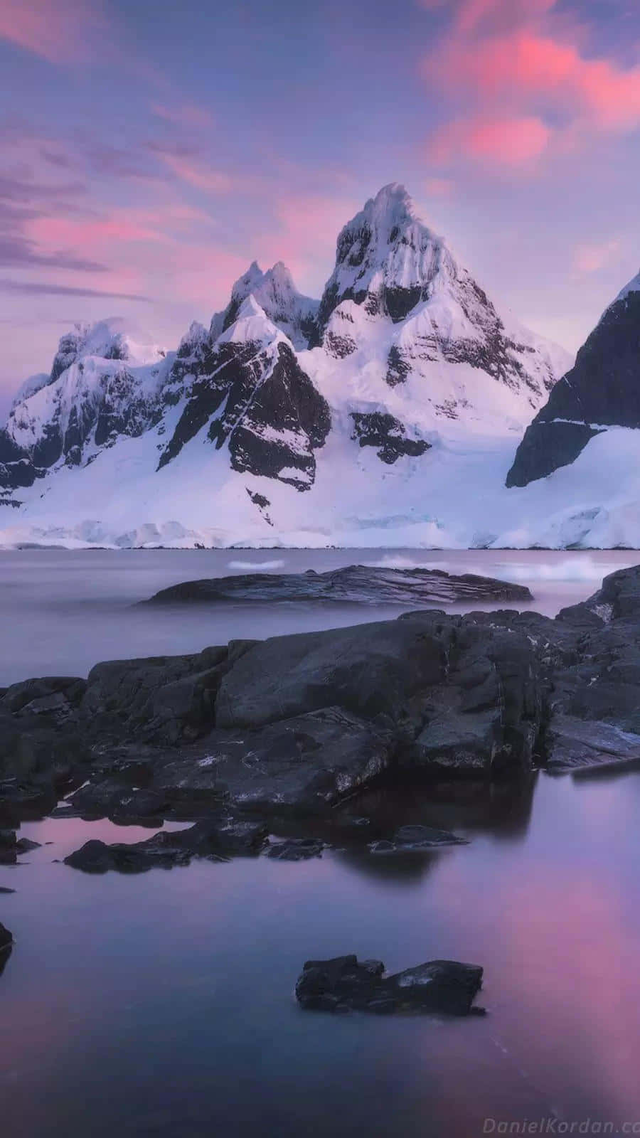 Antarctica 桌布 壁紙 — 白雪覆蓋的山峰在粉紅和紫色的暮色天空下倒映在平靜的水面上。