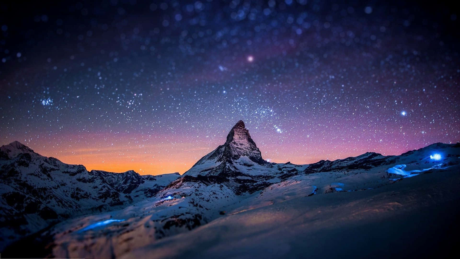 Snowy Mountain 桌布 壁紙 — 白雪覆蓋的山峰在紫色和橙色色調的星空暮色天空下聳立。