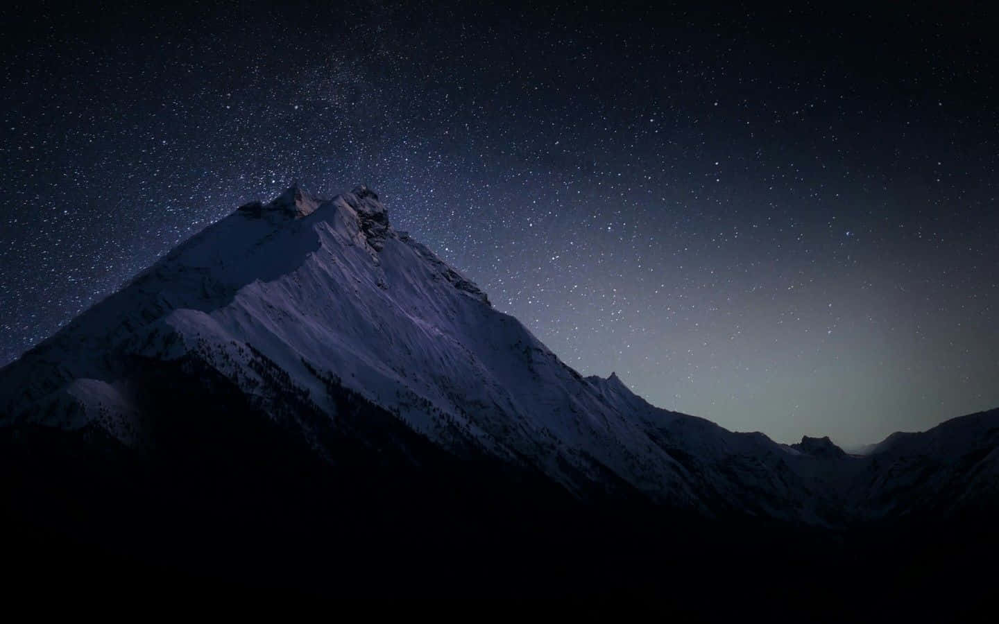 Dark Landscape 桌布 壁紙 — 白雪覆蓋的山峰在繁星點點的夜空下聳立，地平線上有微弱的極光輝光。