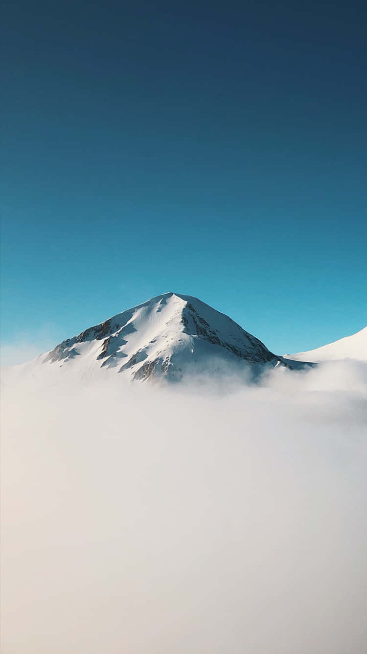 iPhone X 桌布 壁紙 — 白雪覆蓋的山峰在蔚藍天空下，雄偉地聳立於雲海之上。