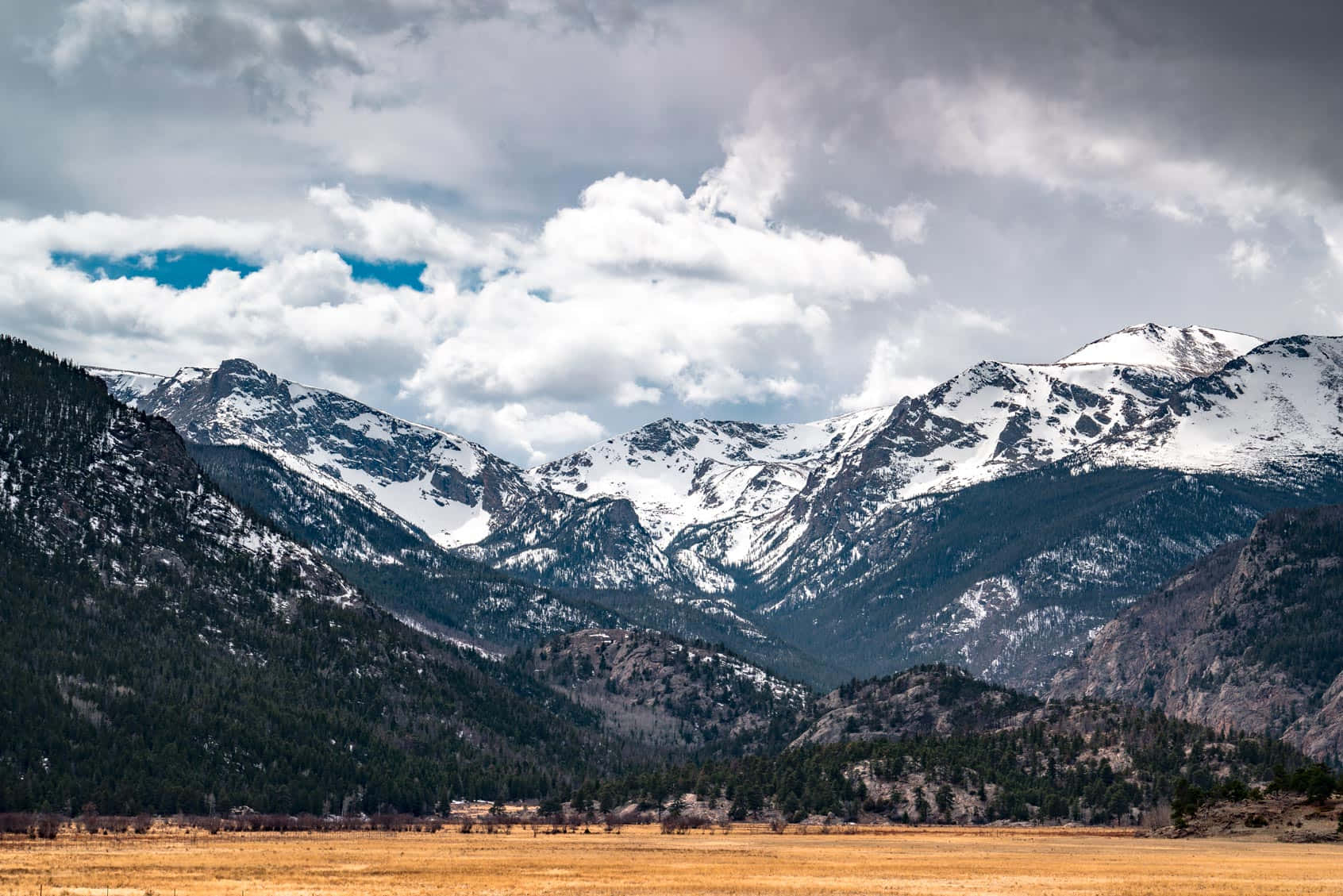 Colorado Mountain 桌布 壁紙 — 白雪覆蓋的山峰在藍天白雲下，戲劇性地聳立在金色山谷之後。