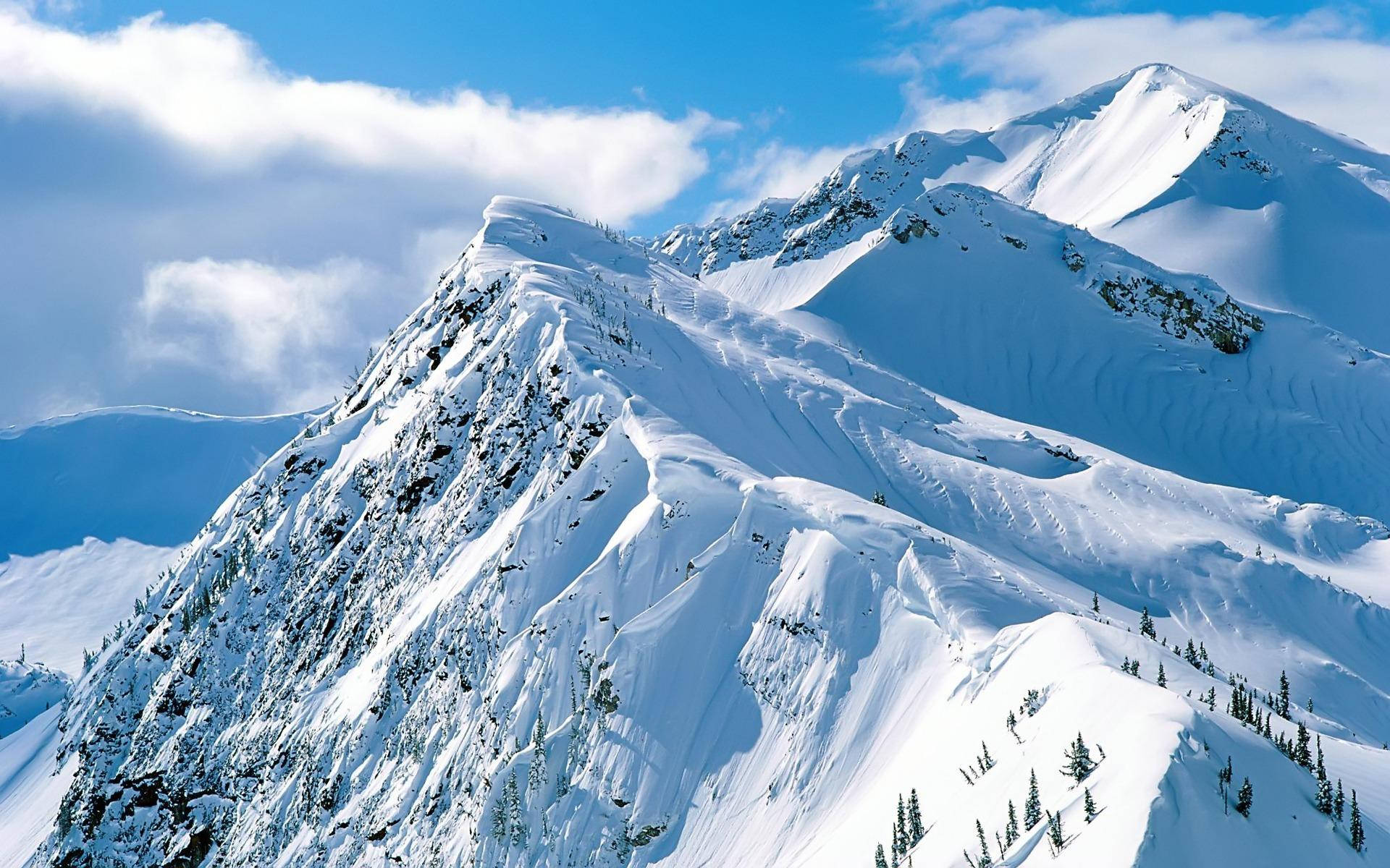 Snowy Mountain 桌布 壁紙 — 白雪覆蓋的山峰在藍天白雲下巍然聳立。