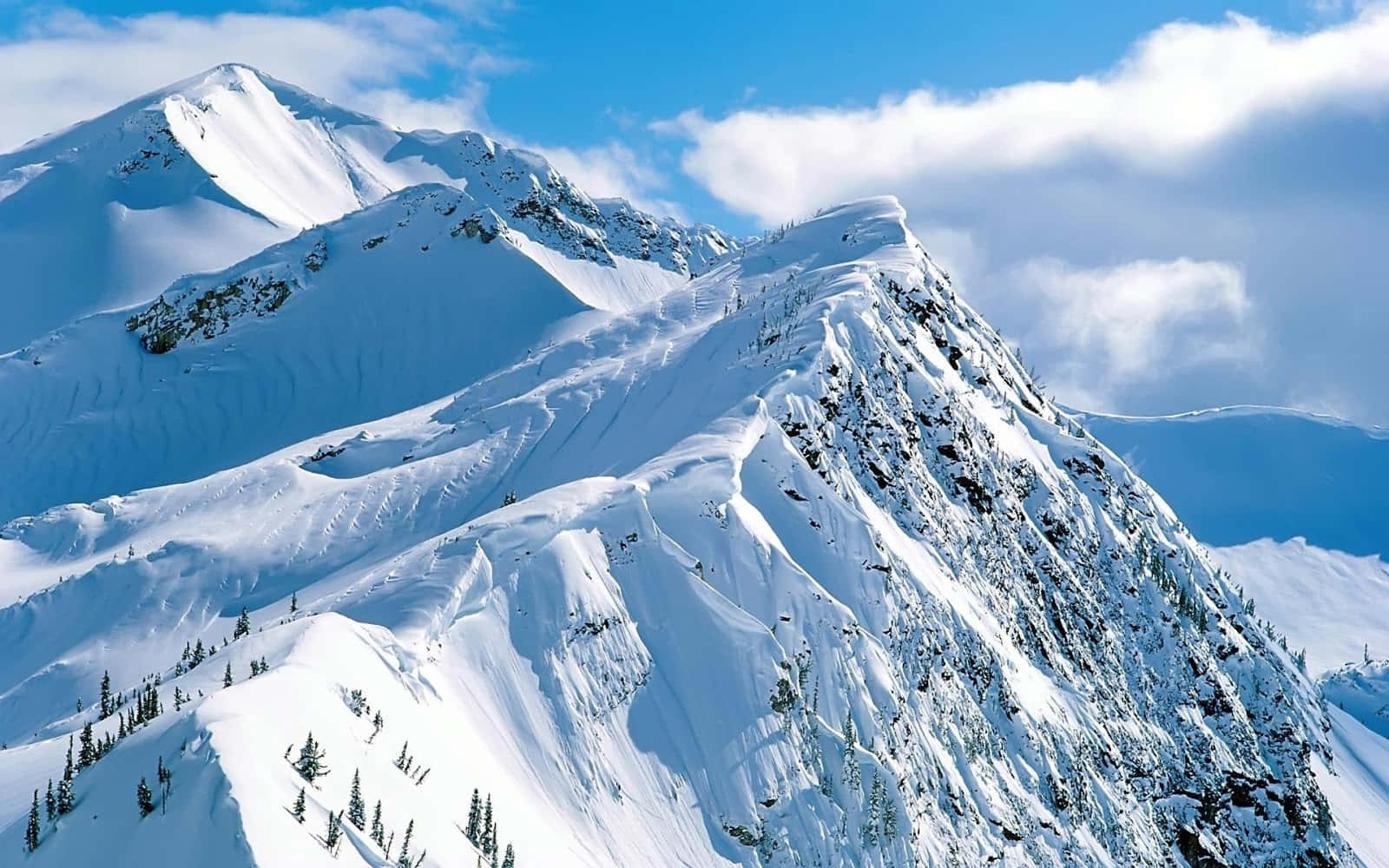 雪山 桌布 壁紙 — 白雪覆蓋的山峰在藍天白雲的映襯下巍然聳立。