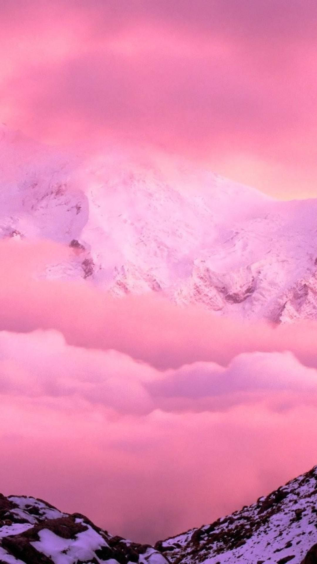 黃昏時分，粉紅色的山脈在雲層之上升起。 — iPhone 14 壁紙