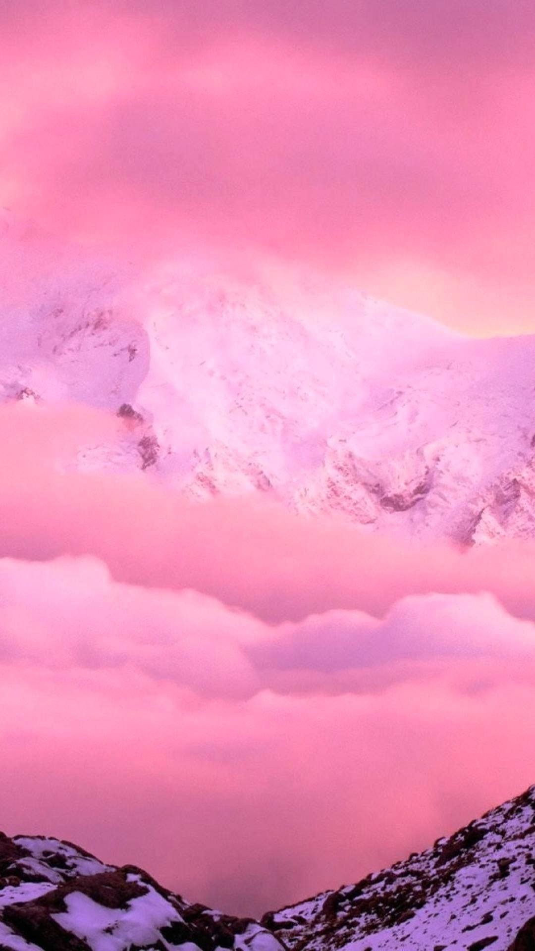 粉紅色系 iPhone 桌布 壁紙 — 白雪覆蓋的山峰在黃昏時分穿透夢幻的粉紅和紫色雲海。