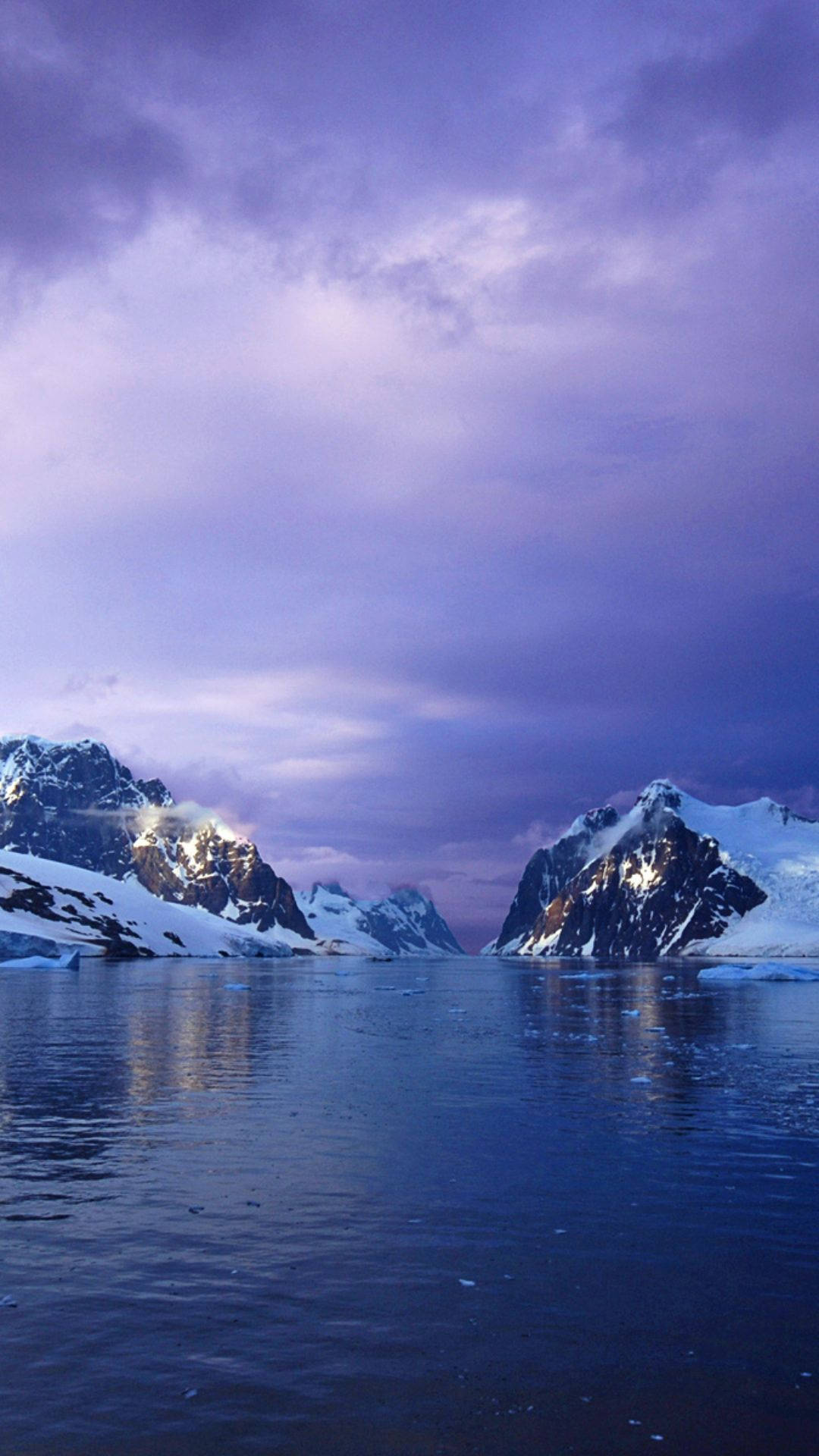 Antarctica 桌布 壁紙 — 白雪覆蓋的山峰從冰冷的水域中升起，在戲劇性的紫色暮光天空下。