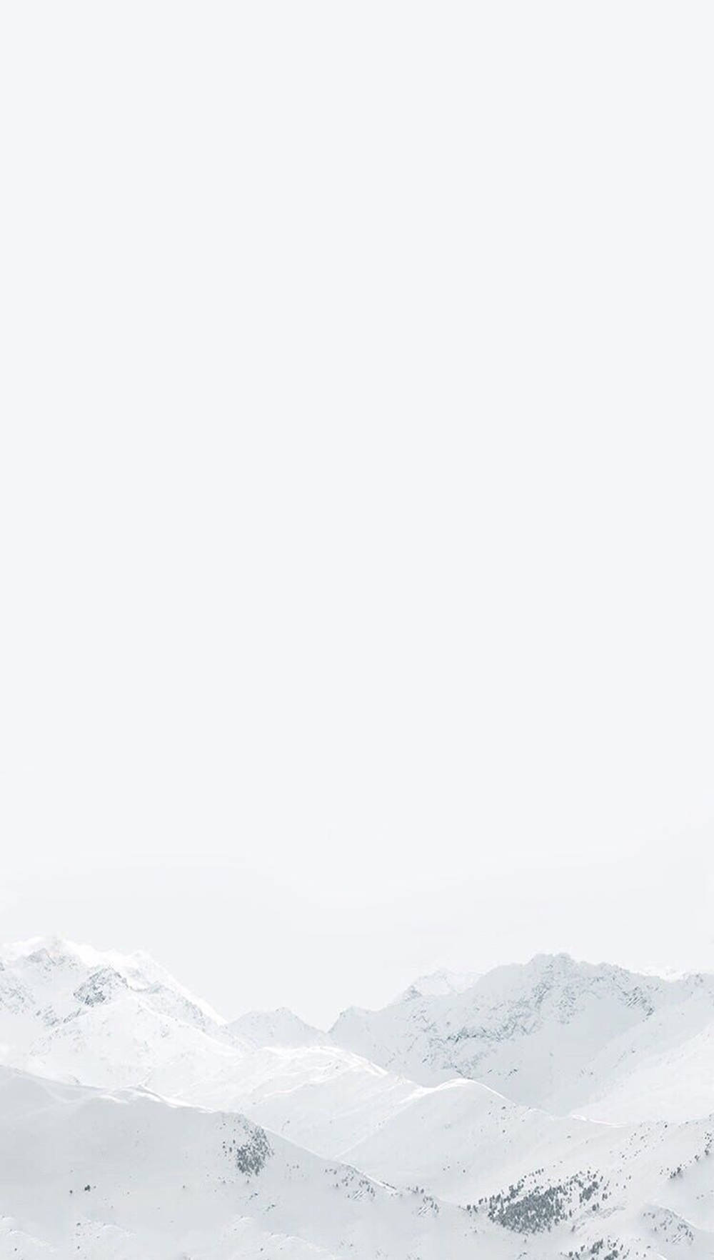 雪山 桌布 壁紙 — 白雪覆蓋的山峰從朦朧的白色天空中浮現，呈現極簡的冬季景觀。