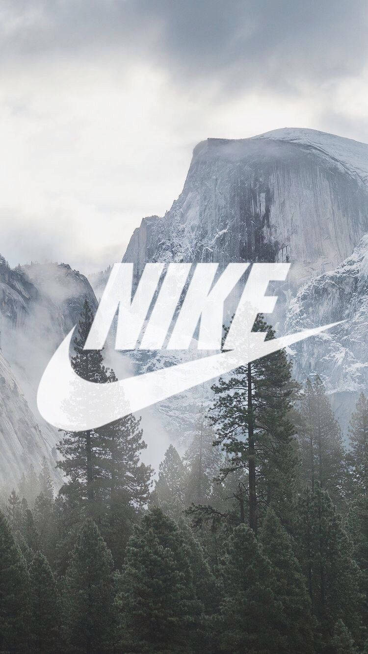 Swoosh 桌布 壁紙 — 白雪覆蓋的山峰聳立在常青樹林後方，並疊加了一個大型白色Nike標誌。