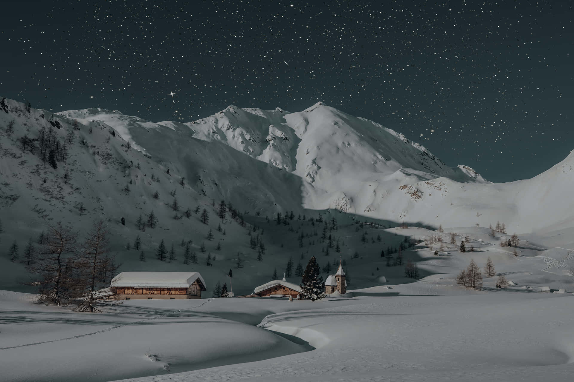  壁紙 — 白雪覆蓋的山村，星空下木屋和松樹上方閃爍的星星。