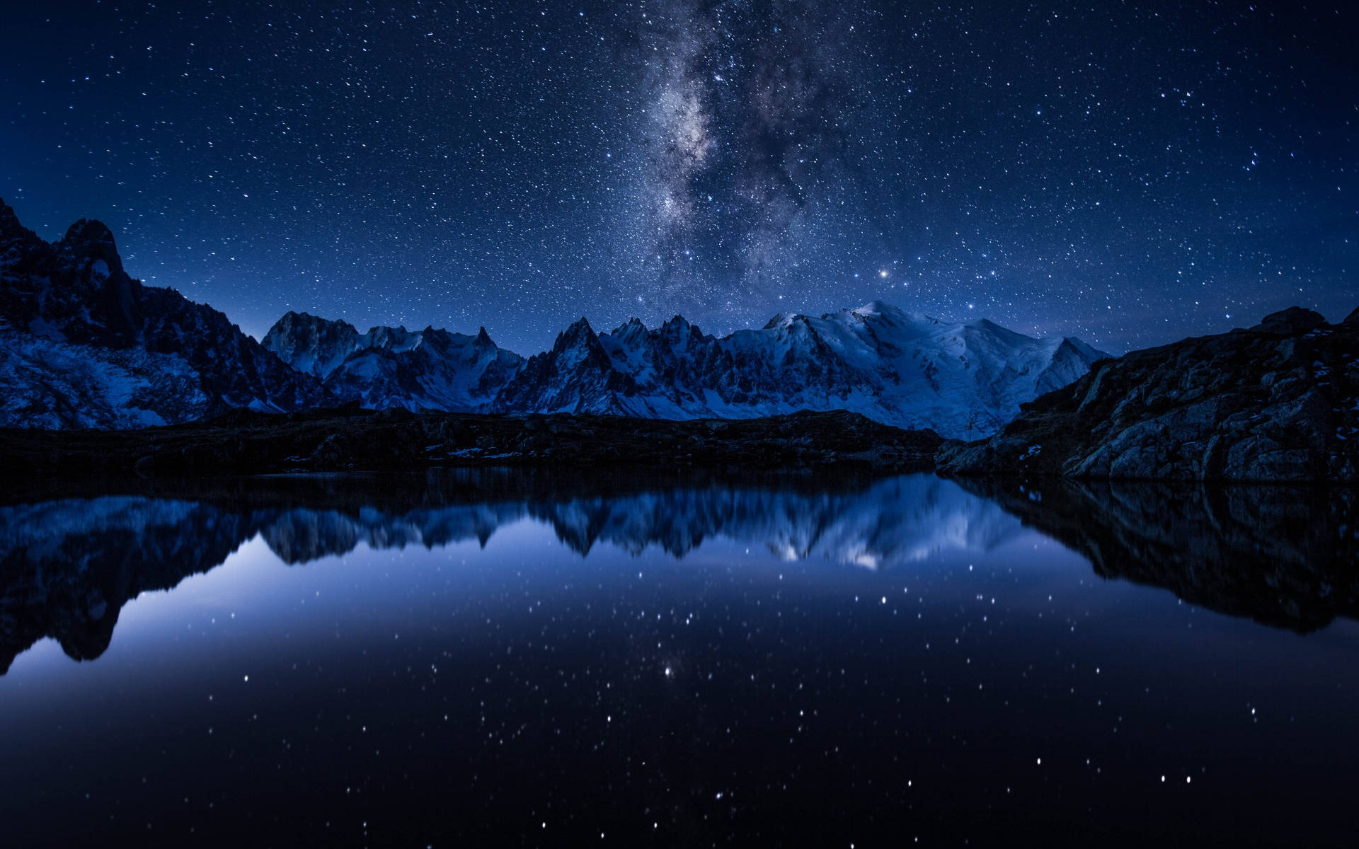 宇宙美學 桌布 壁紙 — 白雪覆蓋的山脈在繁星點點的夜空下，完美倒映在下方平靜的湖面上。