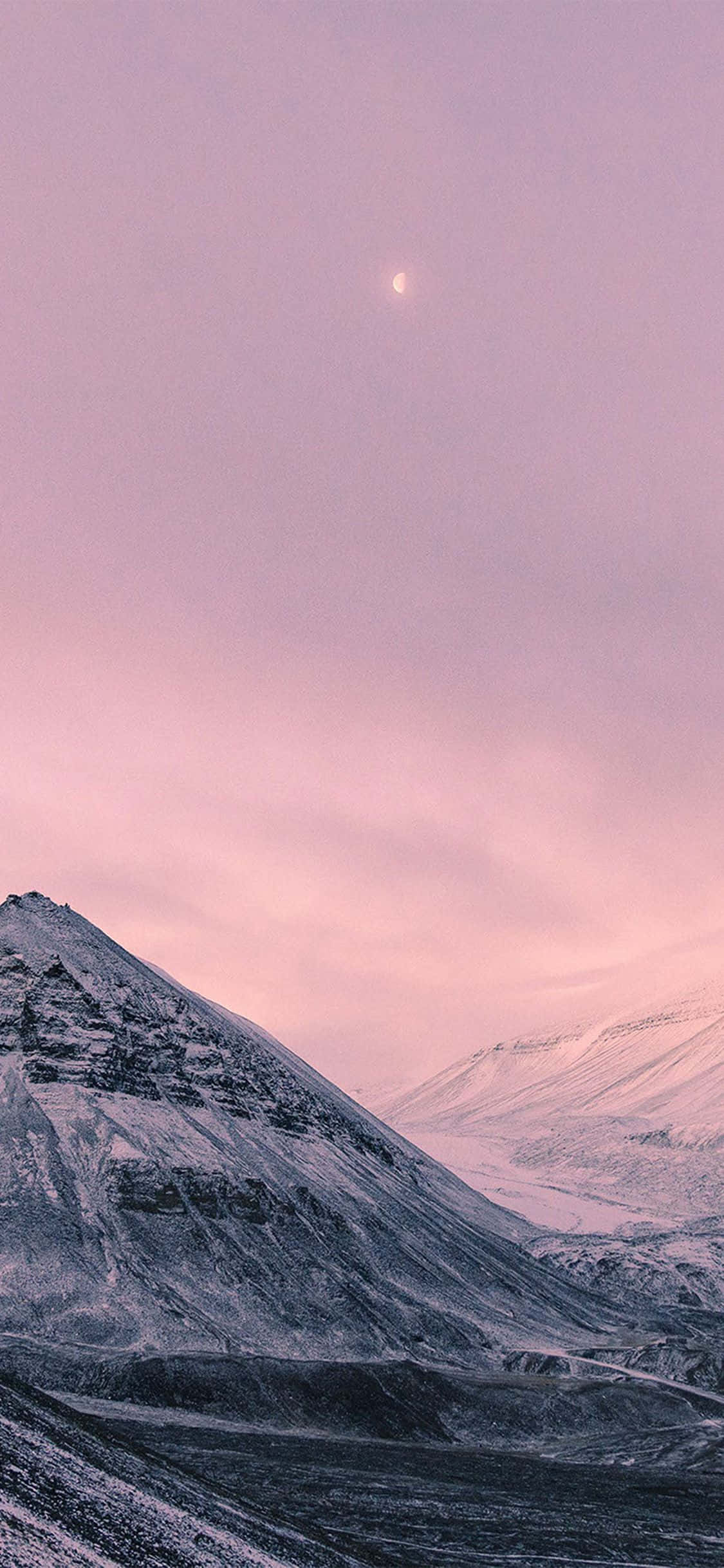 iPhone X Nature 桌布 壁紙 — 白雪覆蓋的山脈沐浴在柔和的粉紅色暮色中，一彎新月在上方閃耀。