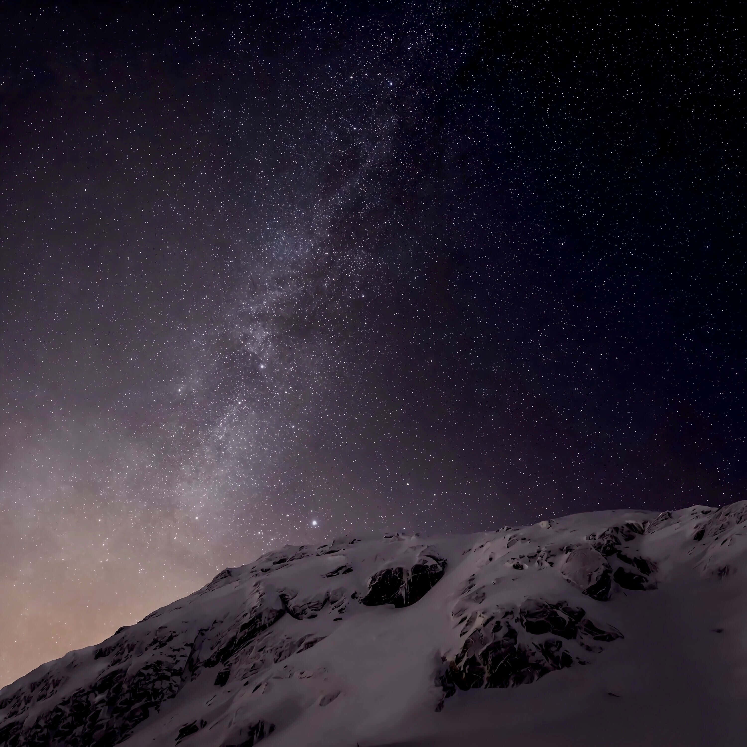 2560x1440 動態圖片 桌布 壁紙 — 白雪覆蓋的山脊，在令人嘆為觀止的星空下，銀河拱跨其上。