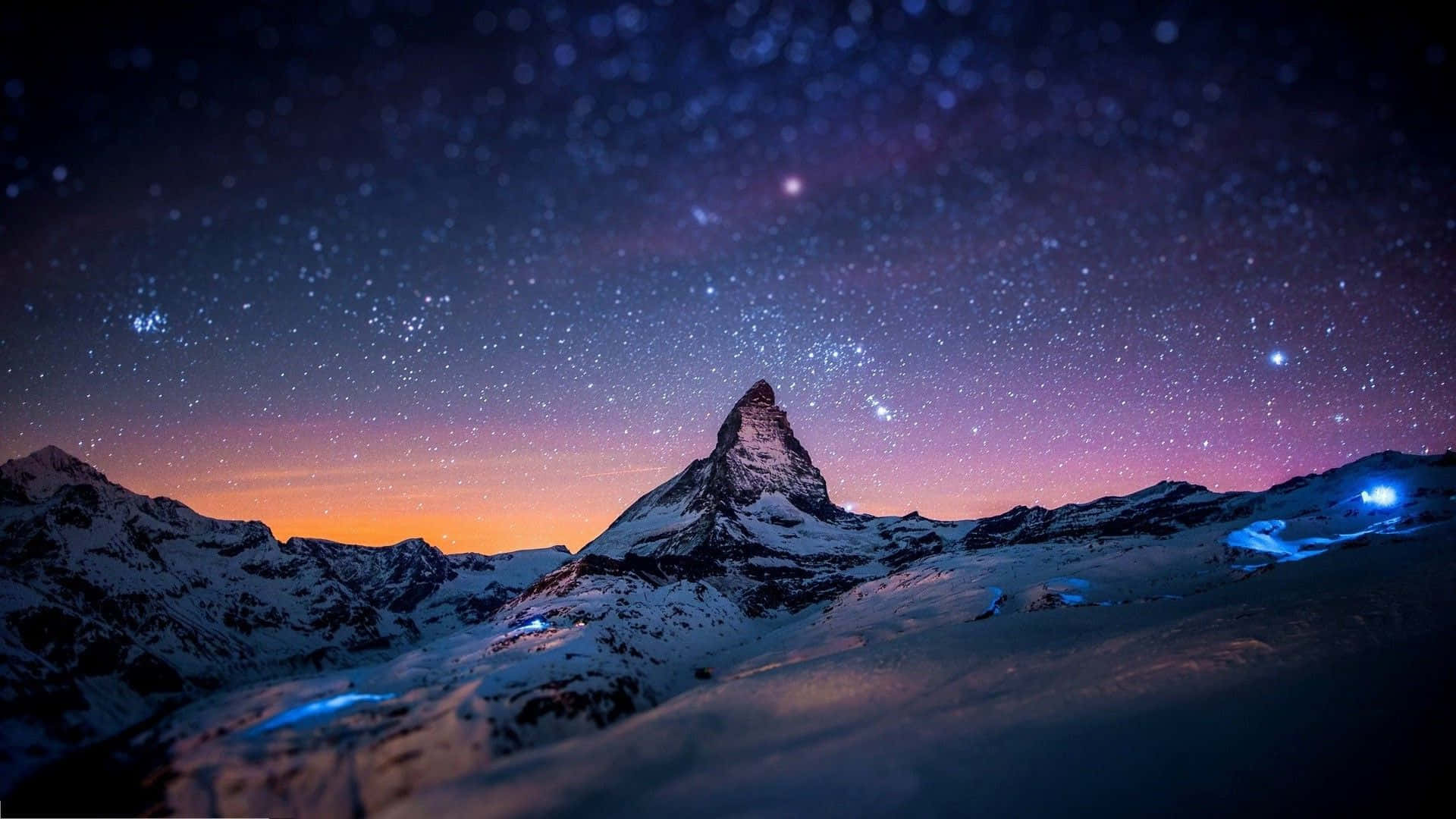 夜空 桌布 壁紙 — 白雪覆蓋的馬特洪峰在星空暮色下聳立，天空呈現紫橙色漸變，雪坡上閃爍著藍色光芒。